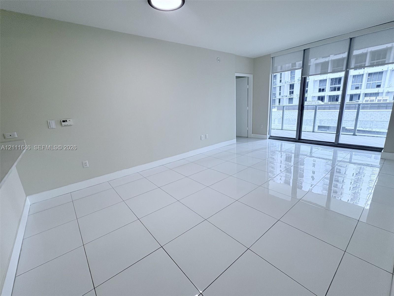 Large-format tile flooring, floor-to-ceiling glass sliding doors, and neutral wall tones