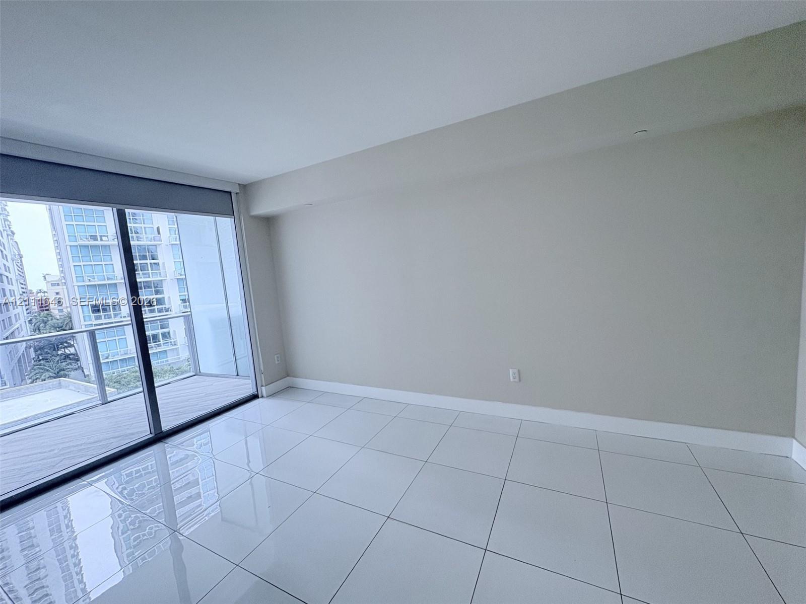 Large-format porcelain tile flooring, floor-to-ceiling glass sliding doors, and access to a private balcony