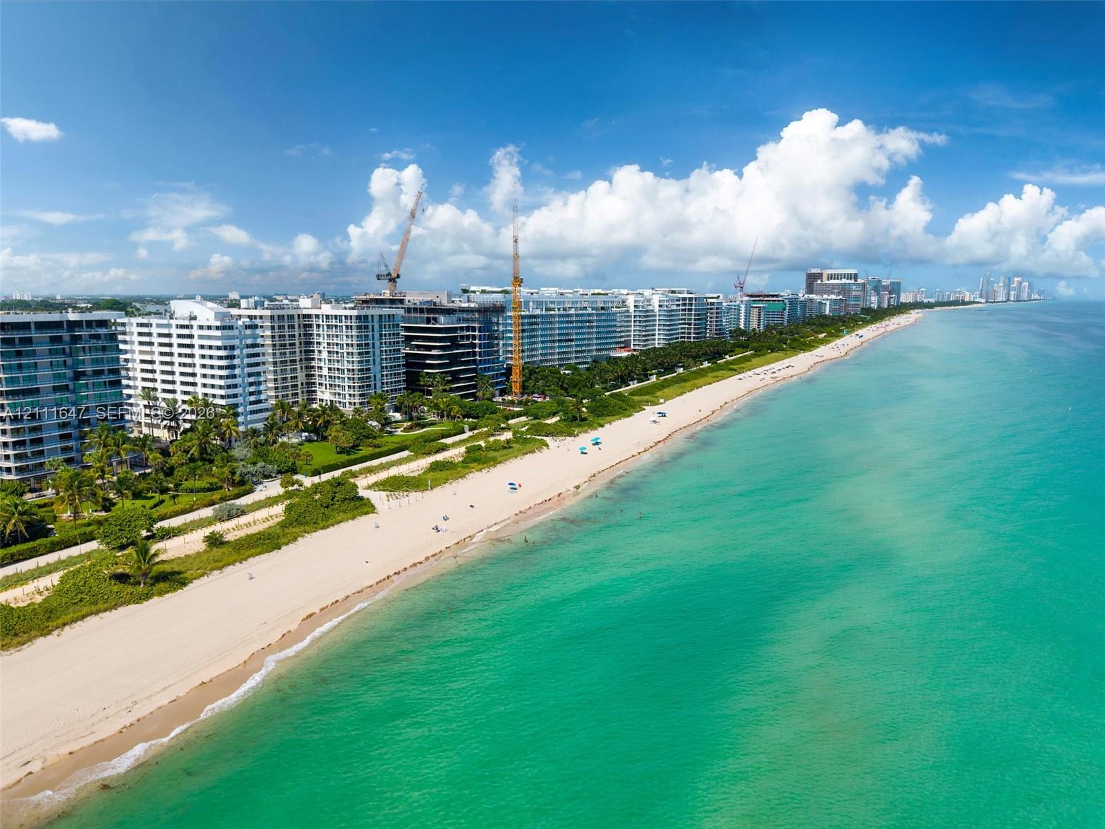 Aerial perspective of coastal multi-unit residential architecture featuring direct beach access, sand shoreline, and ocean frontage