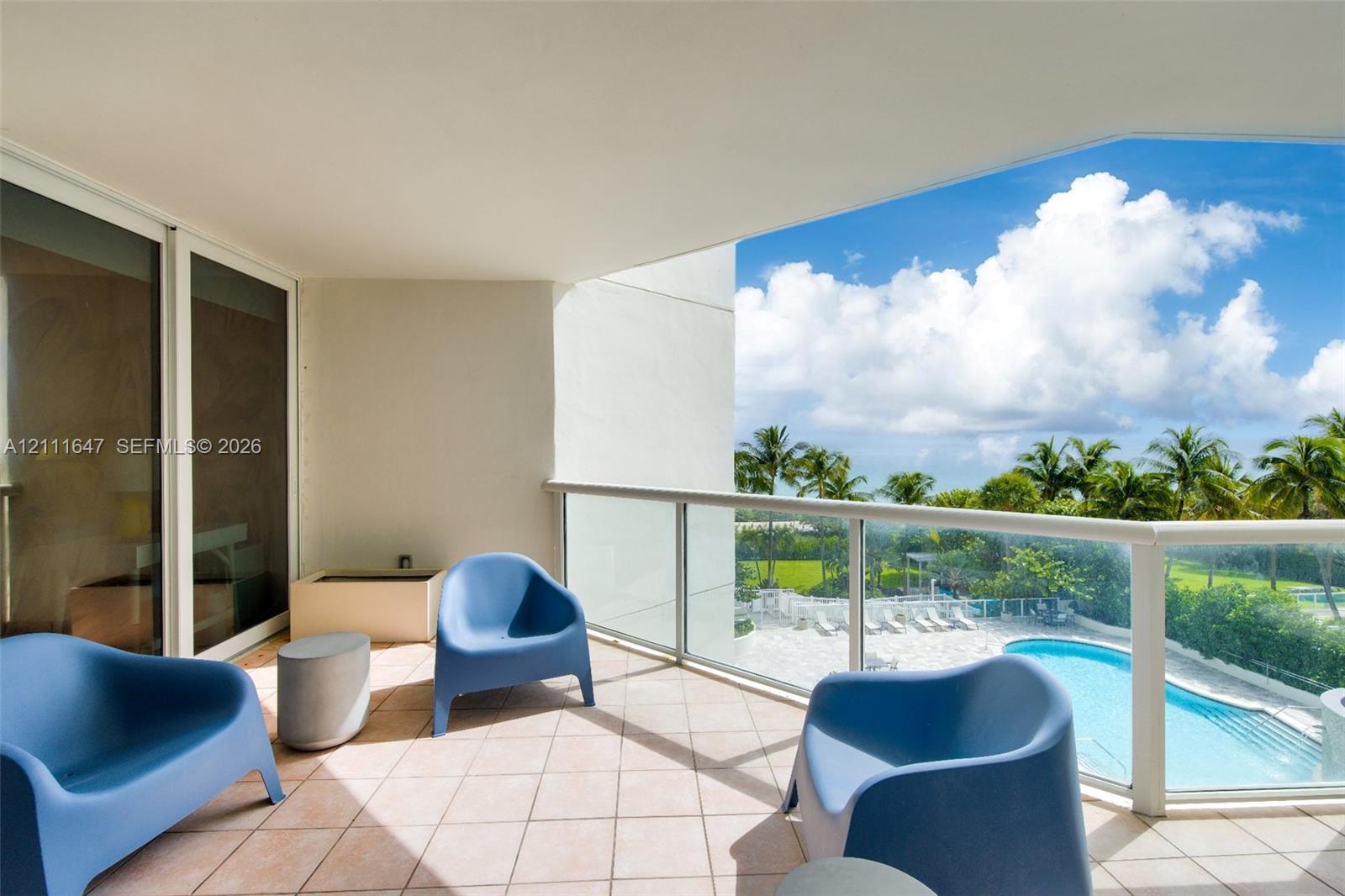 Covered balcony featuring tile flooring and a glass-paneled railing