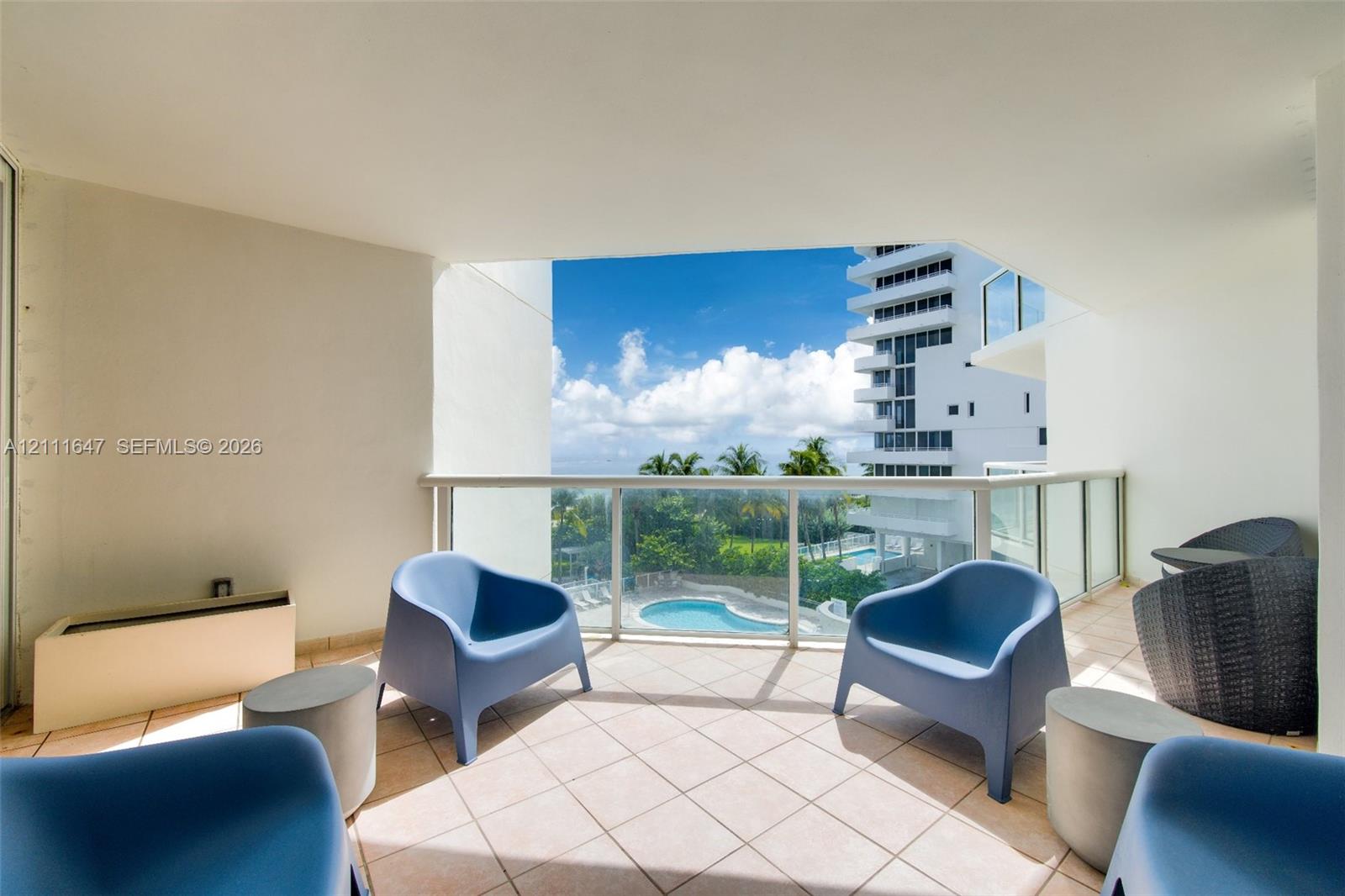 Covered balcony featuring tile flooring and a glass railing