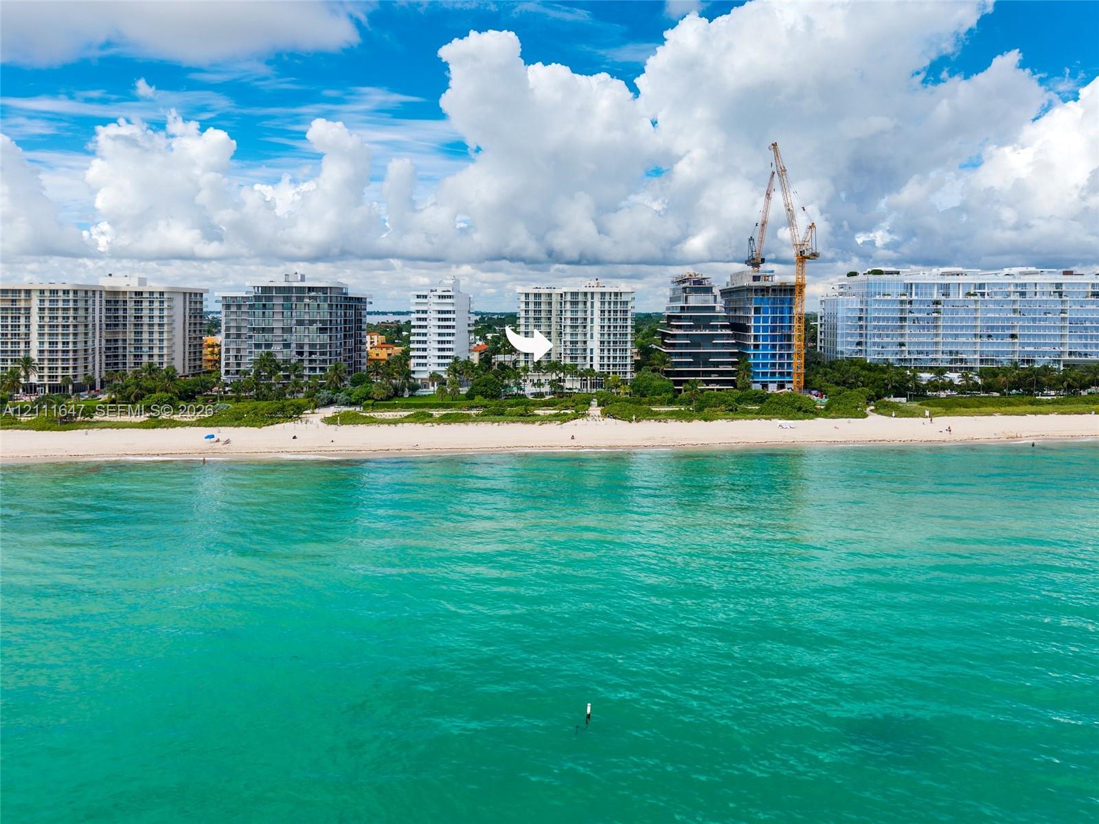 Multi-story high-rise building situated on a direct oceanfront lot featuring sandy beach access and surrounding tropical landscaping