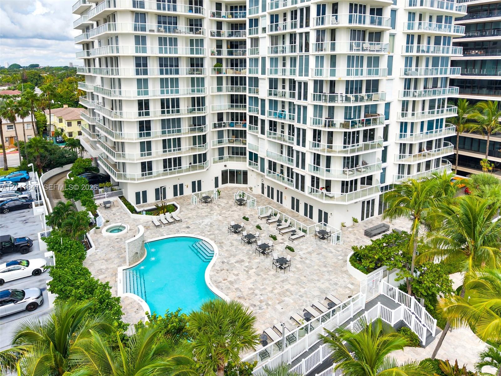 High-rise residential exterior featuring a free-form swimming pool, integrated spa, stone-paver pool deck, and glass-paneled balconies