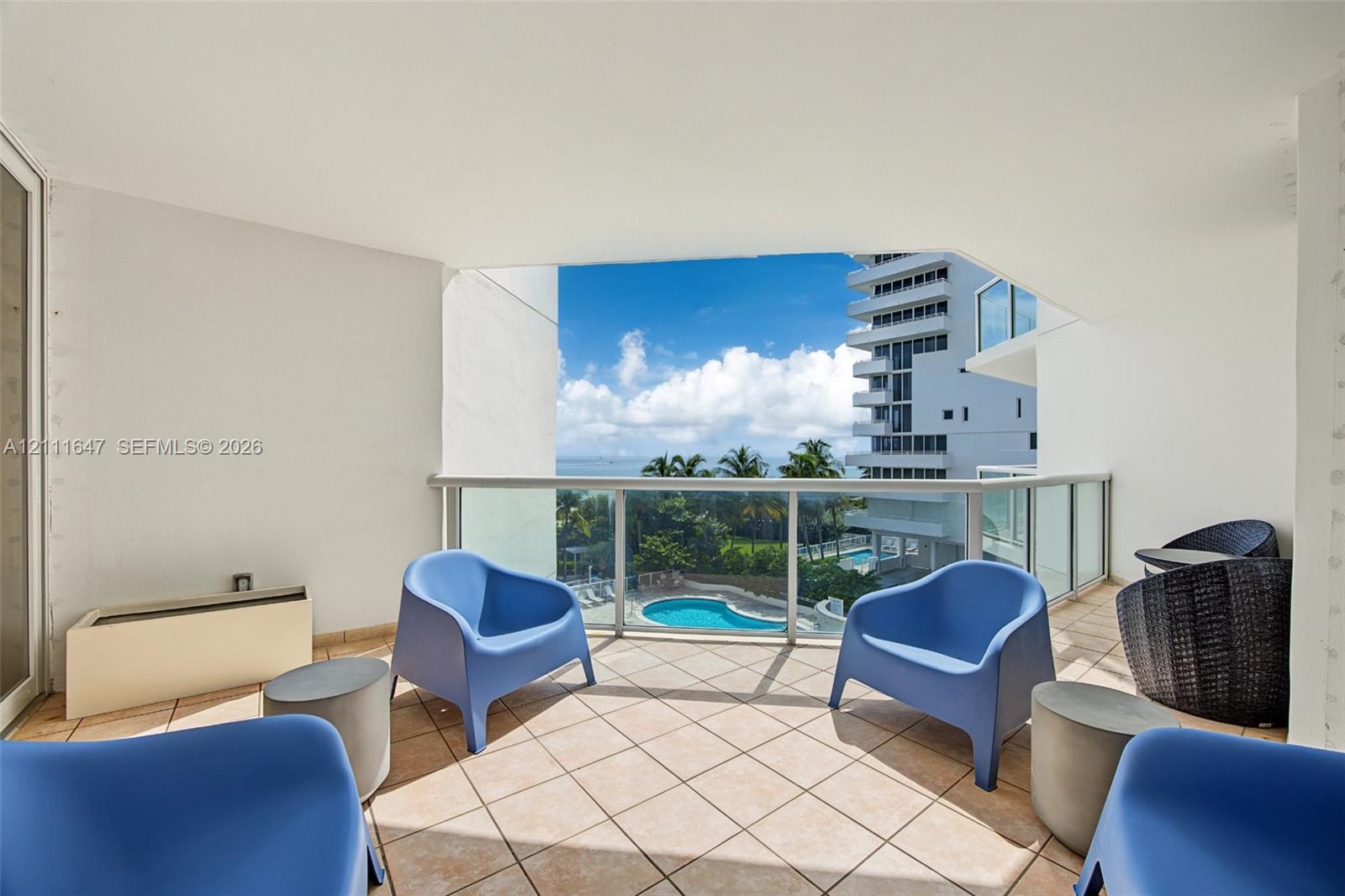 Covered balcony featuring tile flooring and a glass-paneled railing