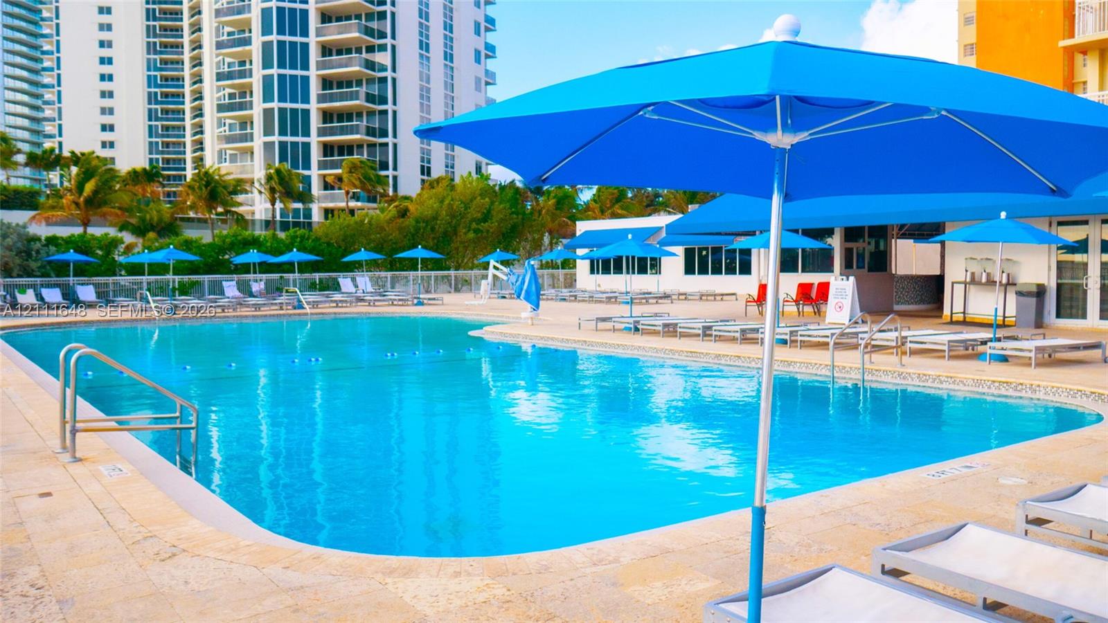 Swimming pool with a stone deck, metal handrails, and a perimeter fence