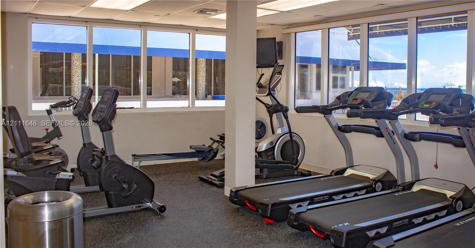 Fitness center featuring rubberized flooring, expansive windows, and recessed ceiling lighting