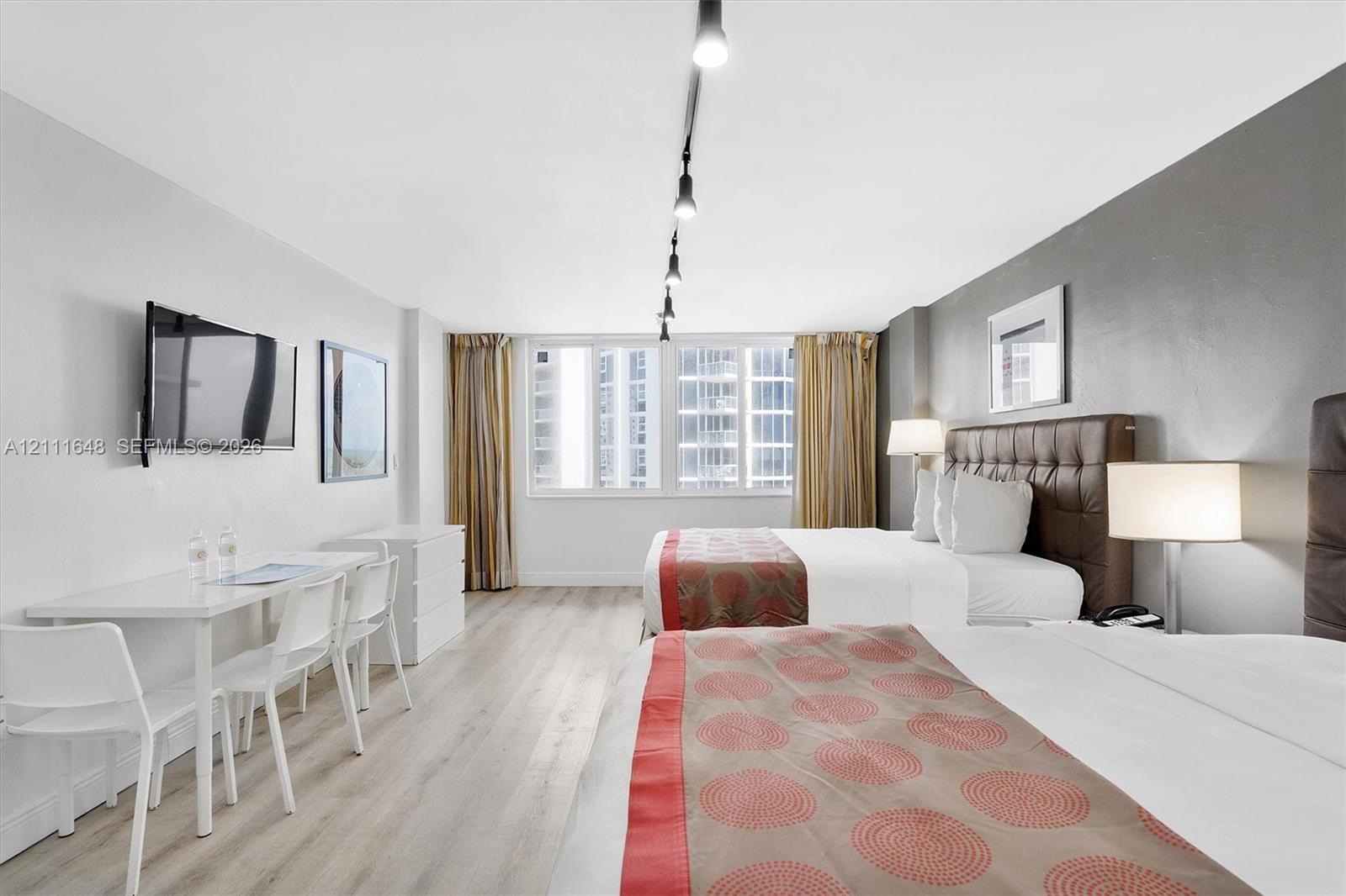 Large windows with natural lighting, wood-finish flooring, track lighting, and a neutral color palette