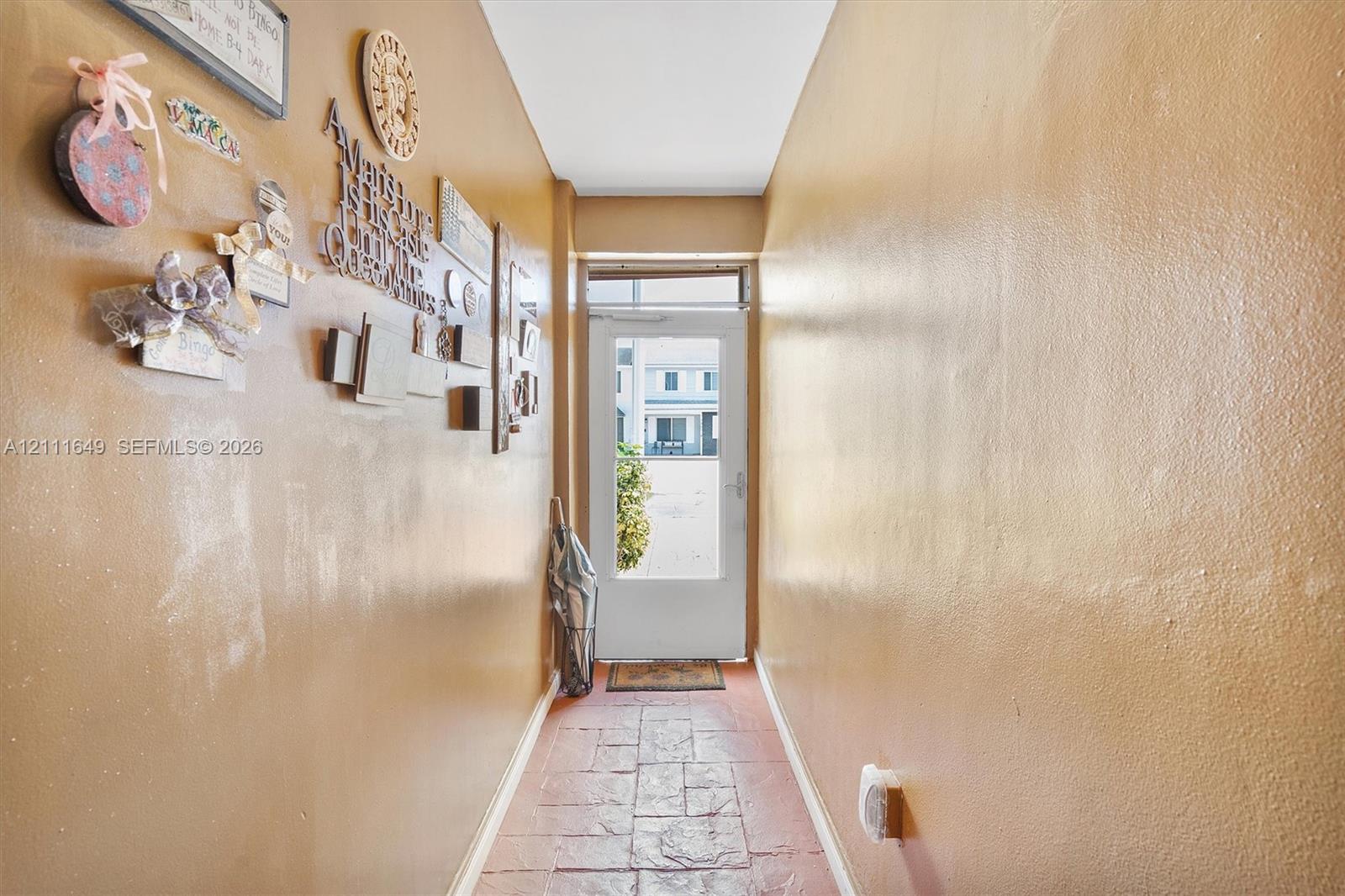 Entryway featuring textured stone-style tile flooring and a glass-paneled exterior door with an overhead transom window
