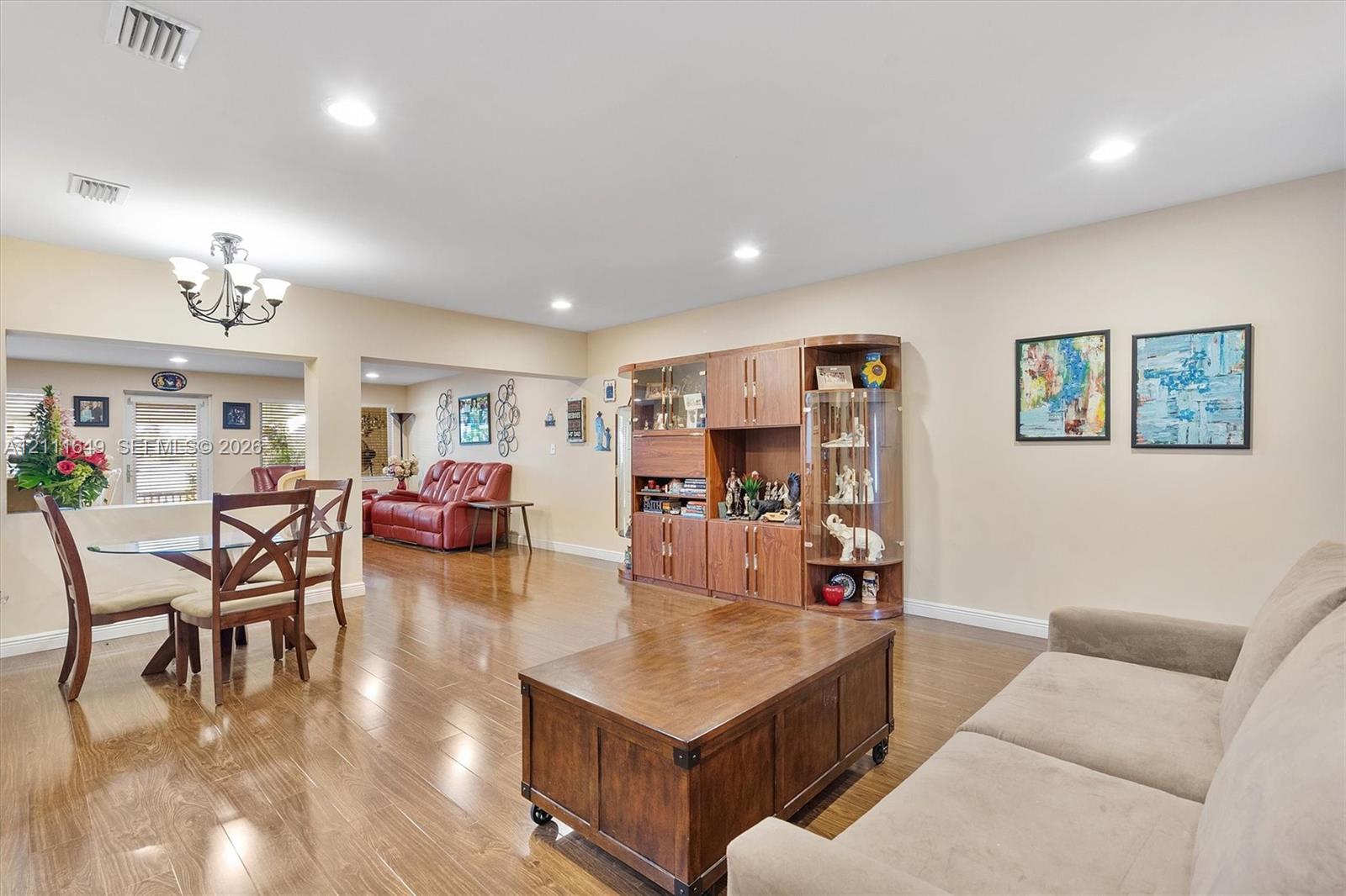 Open-concept interior featuring wood-finish flooring, recessed lighting, and built-in cabinetry with glass-front display shelving