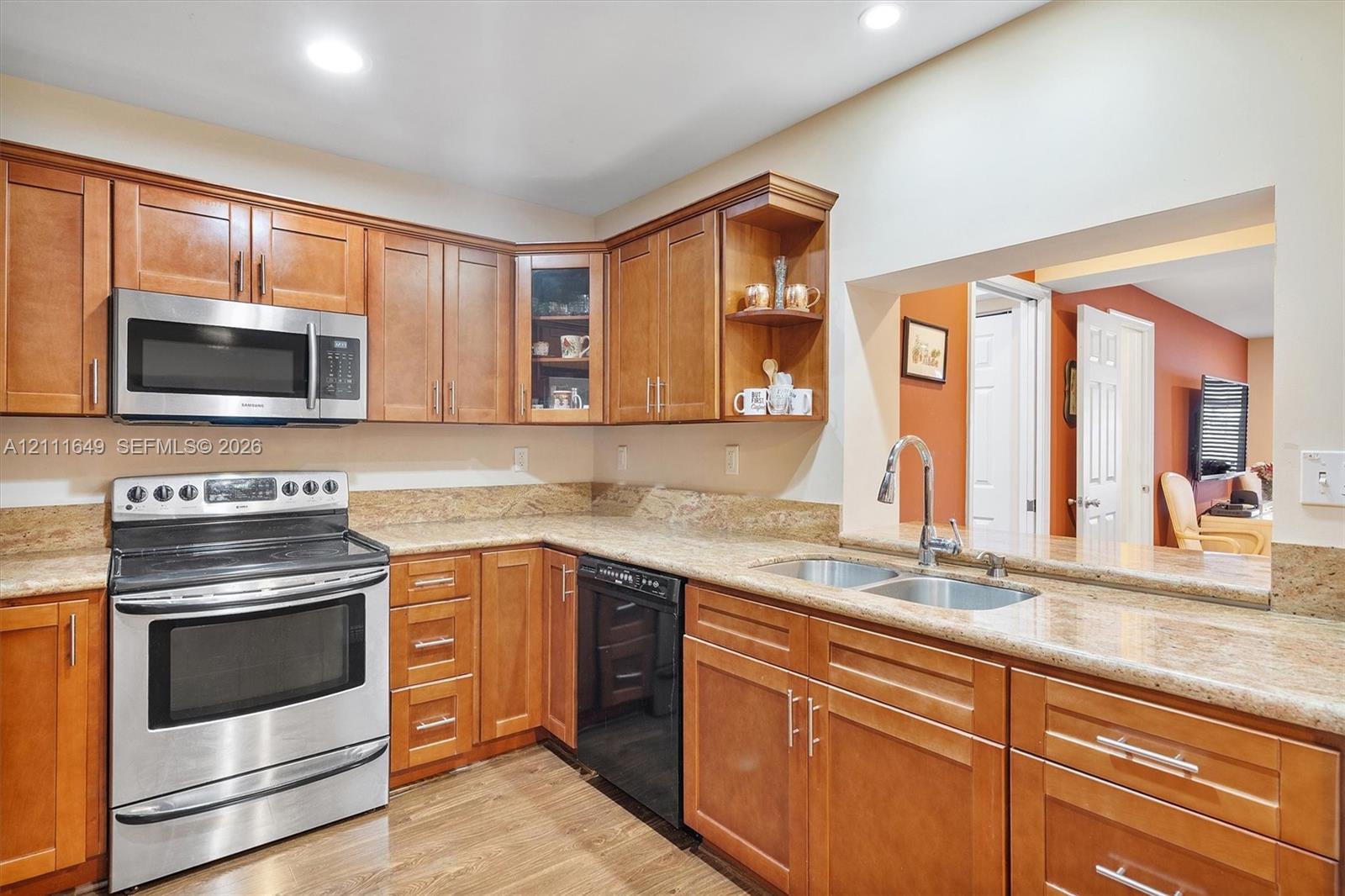 Kitchen featuring wood cabinetry, stone countertops, stainless steel microwave, oven, and recessed lighting