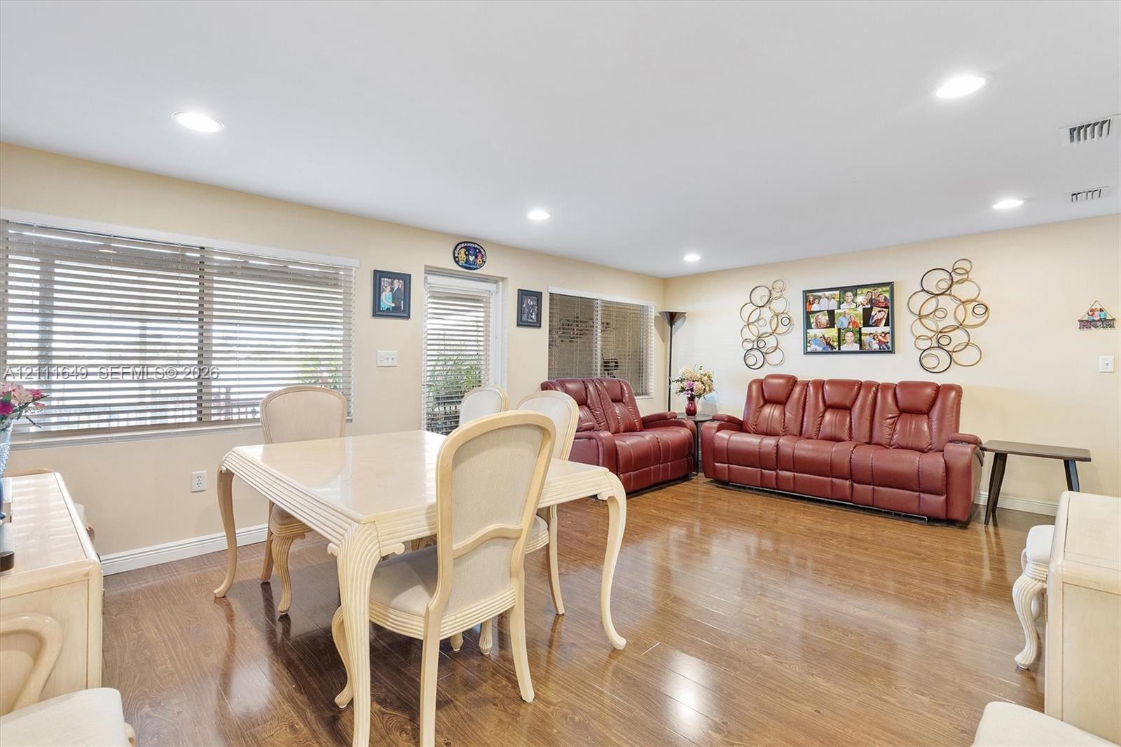 Open-concept interior featuring wood-finish flooring, recessed lighting, and expansive windows with horizontal blinds