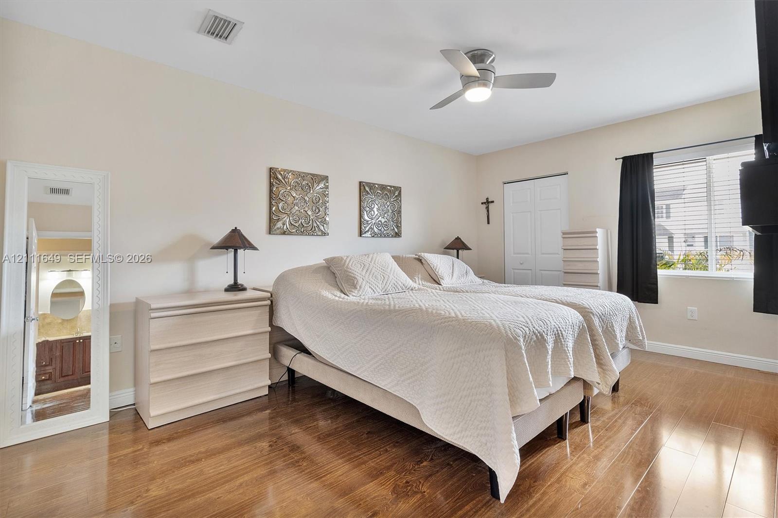Room featuring wood-finish flooring, a ceiling fan with integrated lighting, and a dual-panel closet door