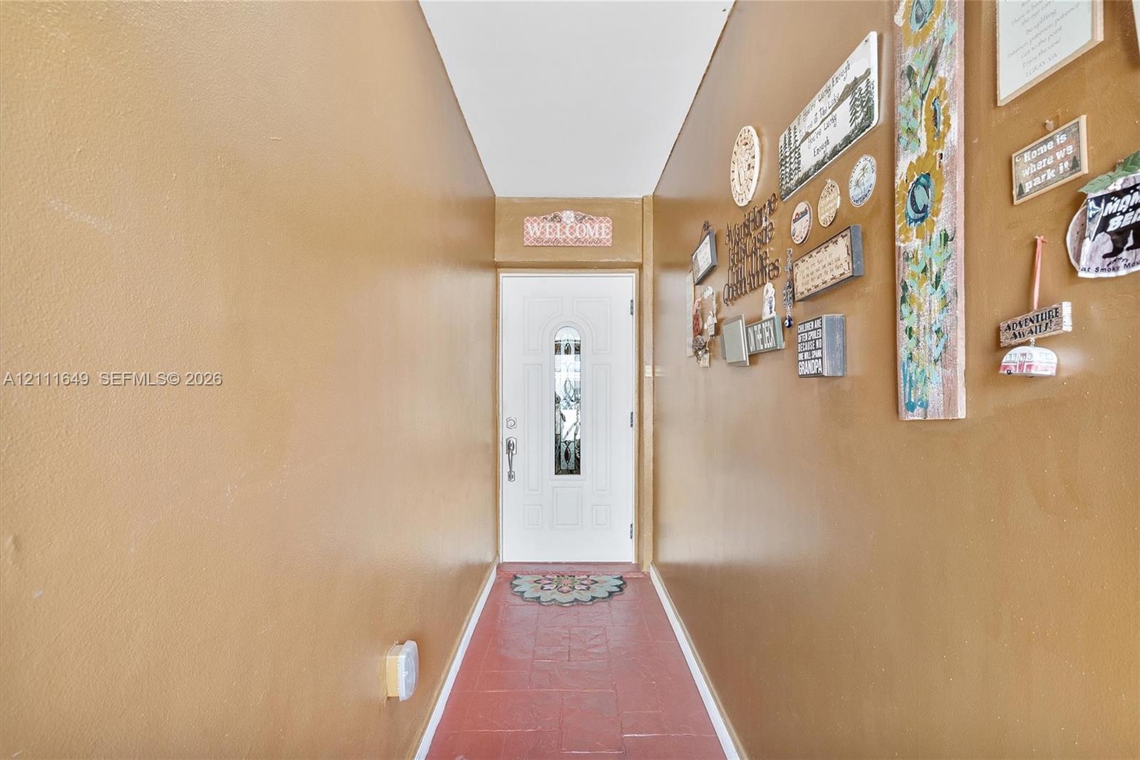 Entrance featuring a white exterior-style door with a decorative glass insert, metal hardware, and tiled flooring