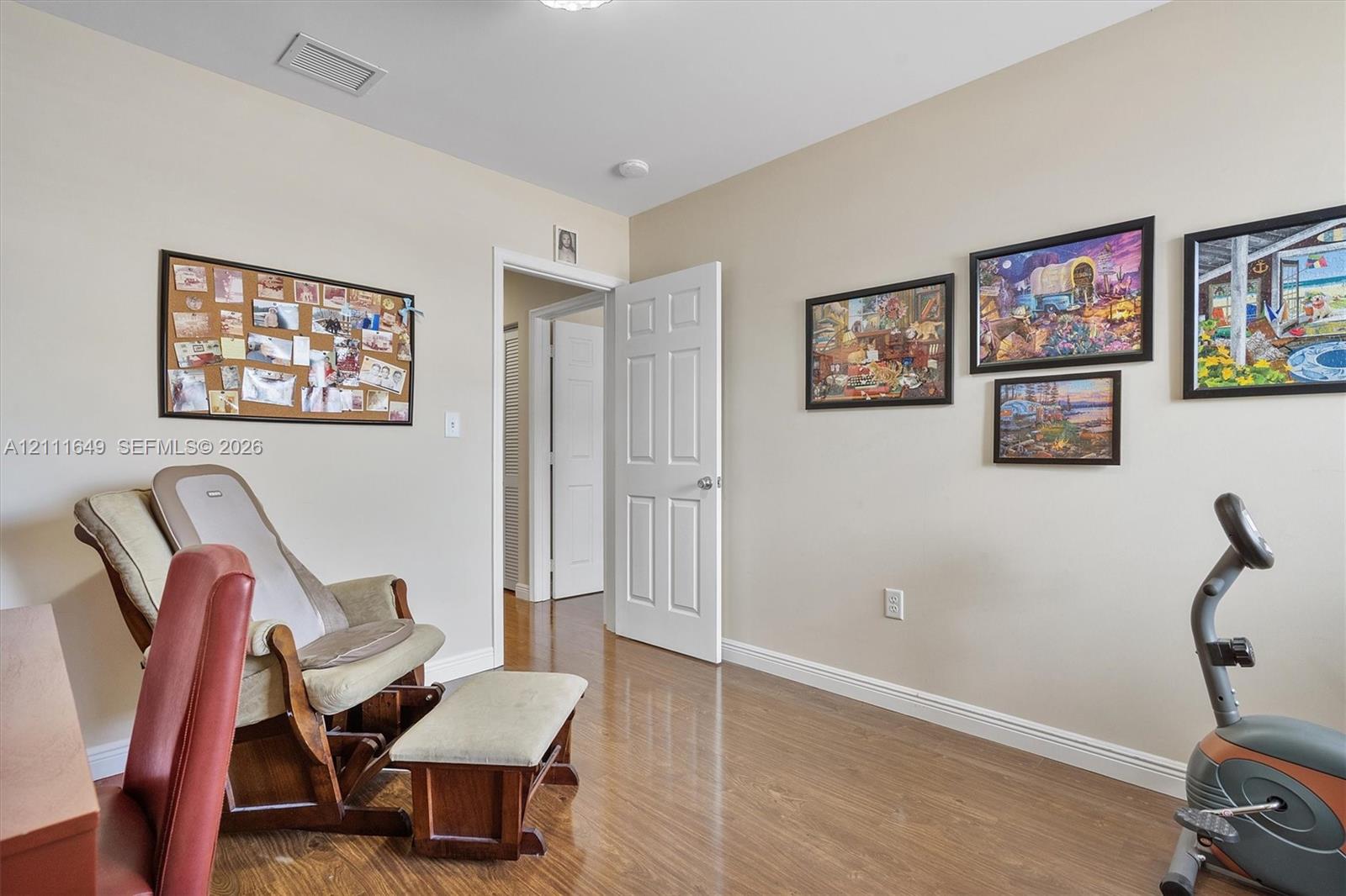 Room featuring wood-finish flooring and a six-panel interior door