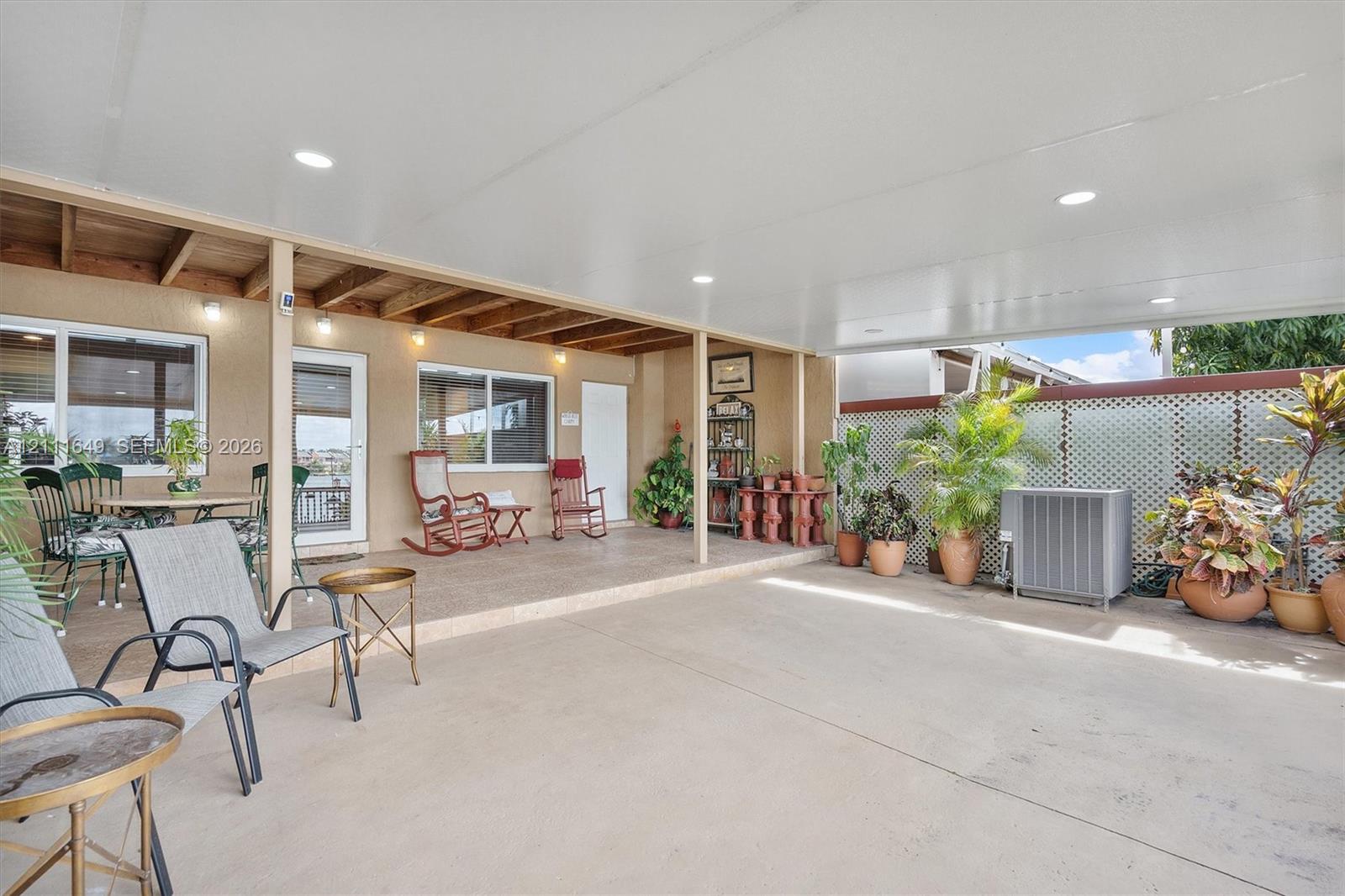 Covered patio featuring an expansive concrete surface, recessed lighting, exposed wood ceiling beams, and decorative lattice wall paneling Covered patio featuring an expansive concrete surface, recessed lighting, exposed wood ceiling beams, and decorative lattice wall paneling