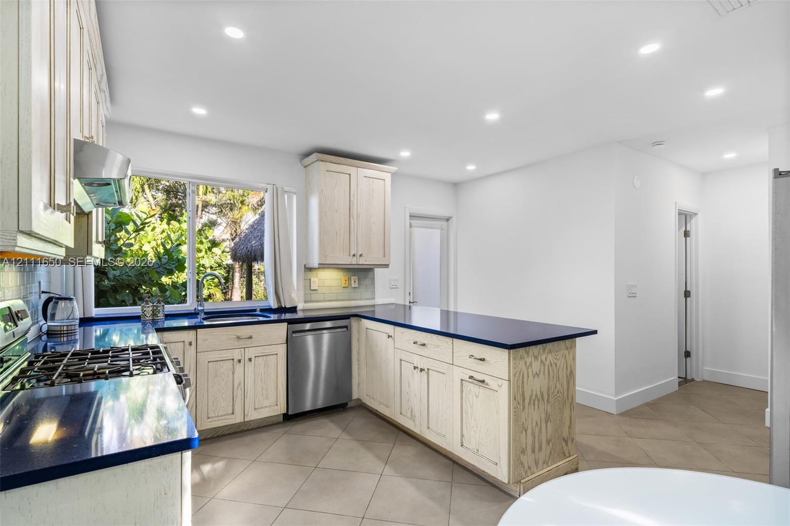 Kitchen featuring light-finish cabinetry, solid-surface countertops, stainless steel appliances, tile flooring, and recessed lighting