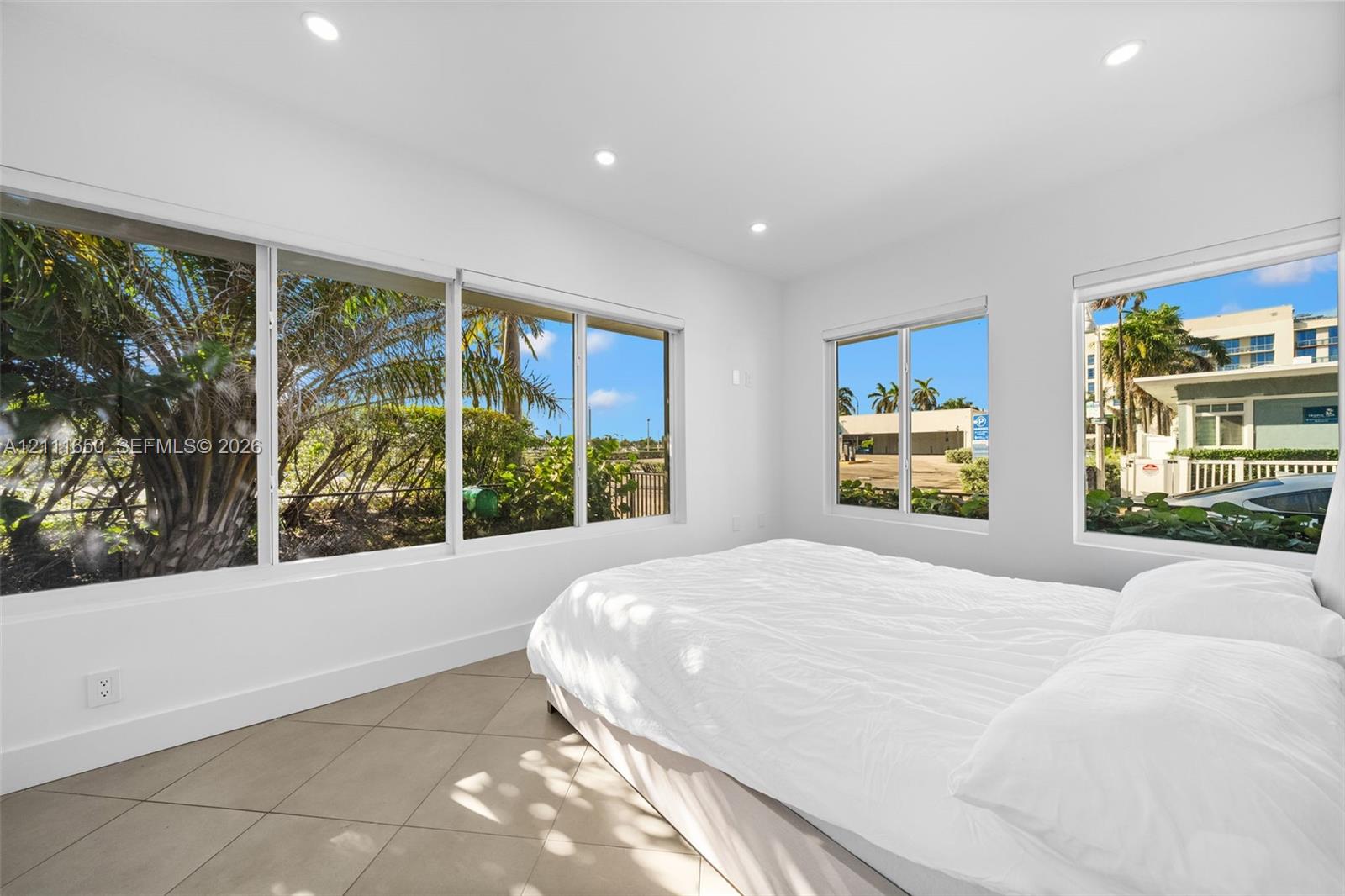 Large-format windows, neutral tile flooring, and recessed ceiling lighting