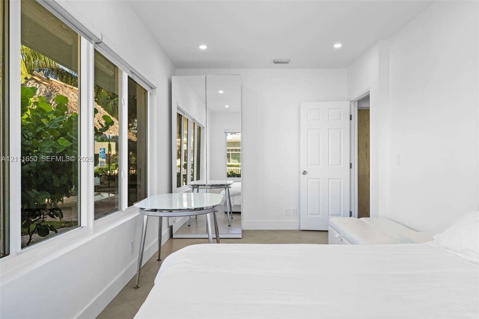 Room featuring large windows with multiple panes, recessed ceiling lighting, and floor-to-ceiling mirrored closet doors