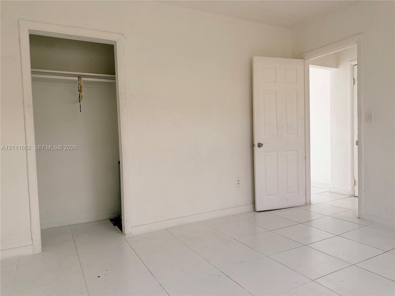 Interior space featuring white ceramic tile flooring, a built-in reach-in closet, and a six-panel door