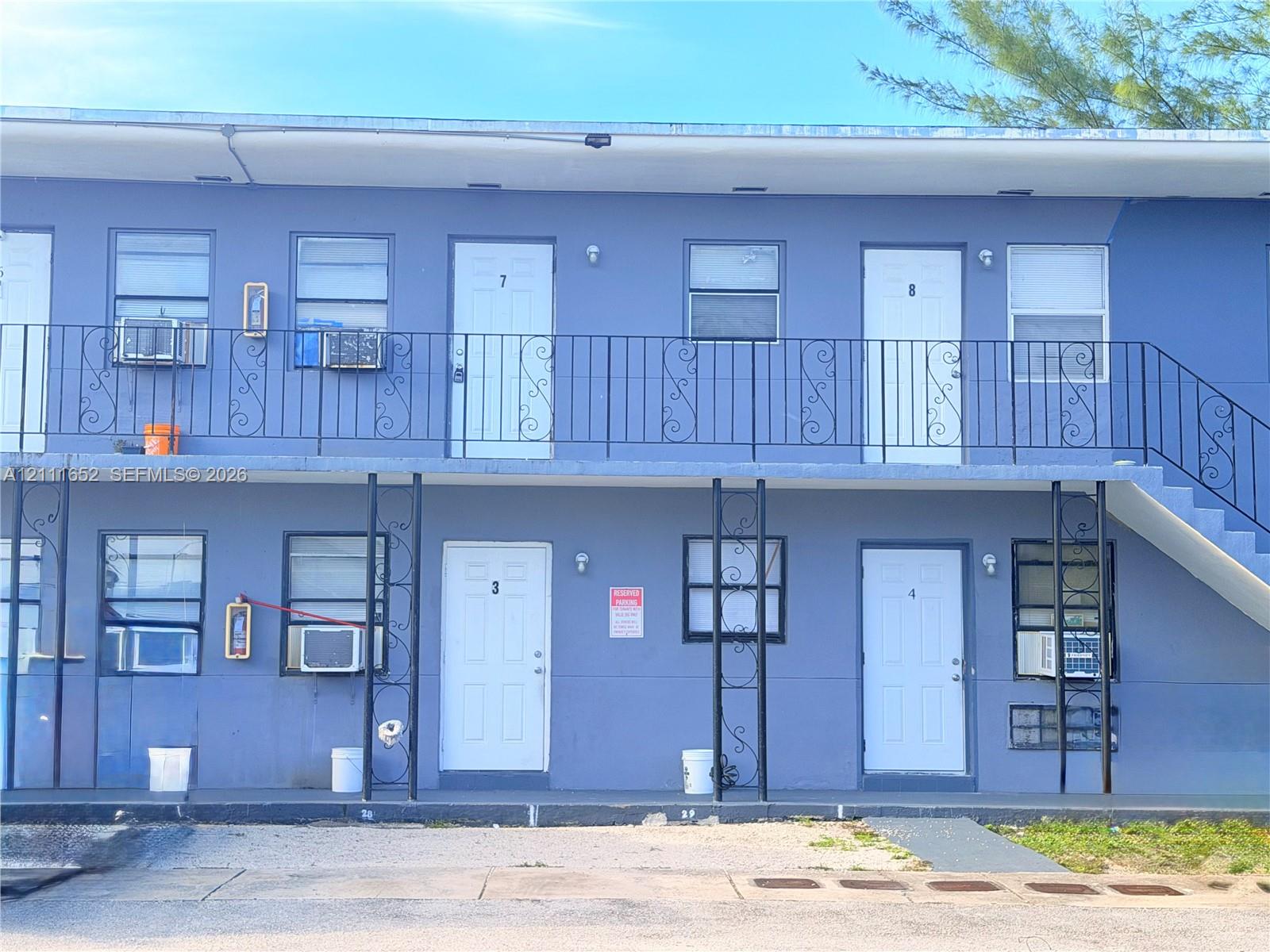 Two-story exterior featuring a flat roofline, painted stucco finish, metal railings, and a staircase