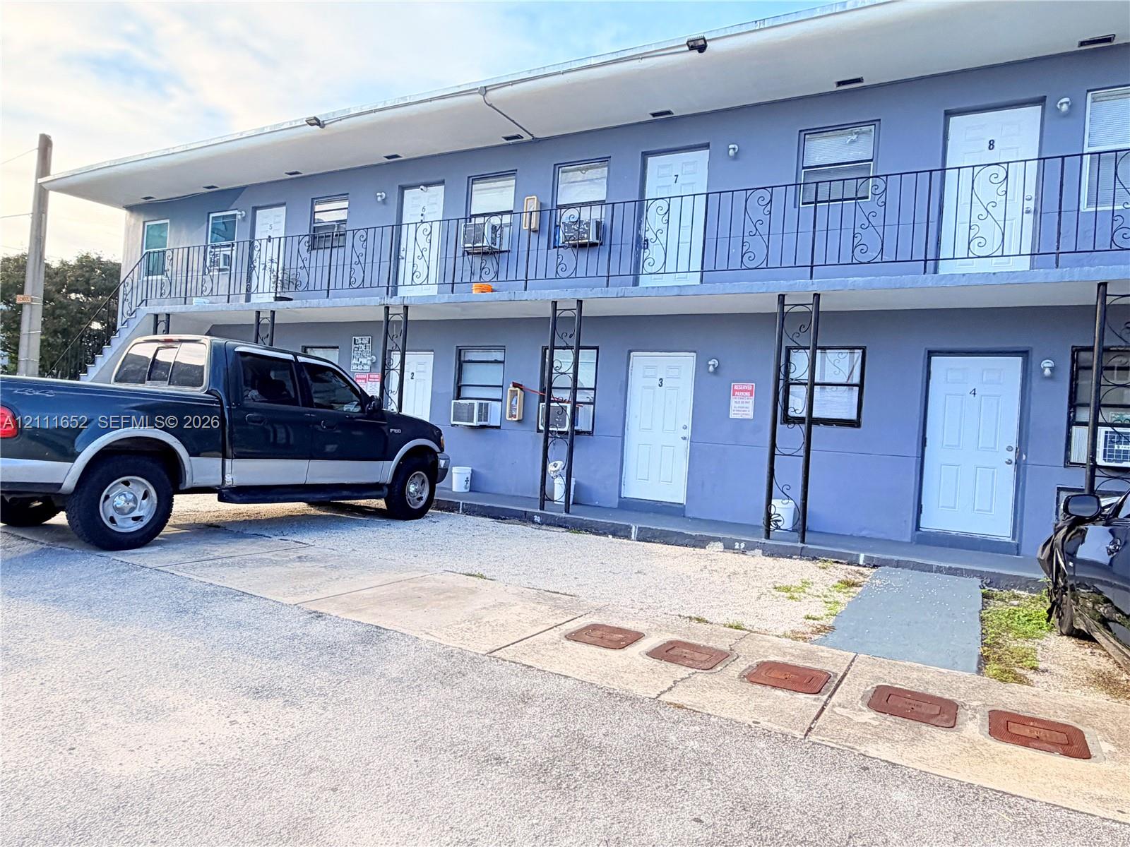 Two-story exterior featuring a concrete-stucco facade, metal balcony railings with decorative ironwork, and paved surface parking Two-story exterior featuring a concrete-stucco facade, metal balcony railings with decorative ironwork, and paved surface parking
