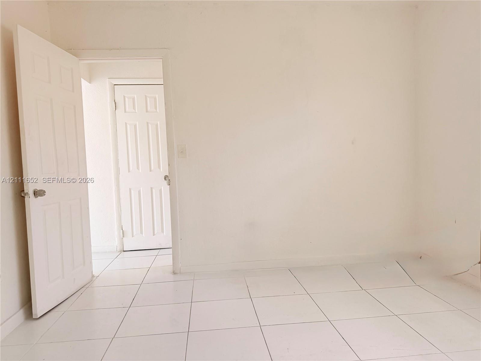 Interior space featuring white tile flooring and dual six-panel interior doors with metallic hardware