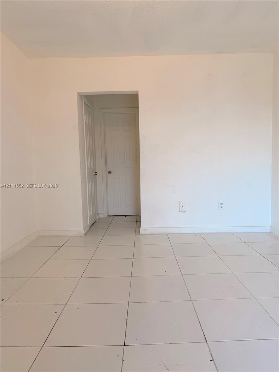 Interior space featuring white-painted walls and light-toned square tile flooring with two interior paneled doors