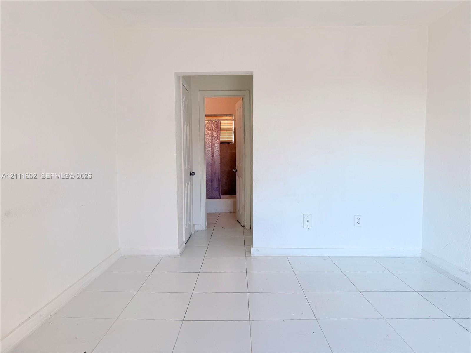 Neutral-toned interior space featuring white wall finishes and uniform tile flooring