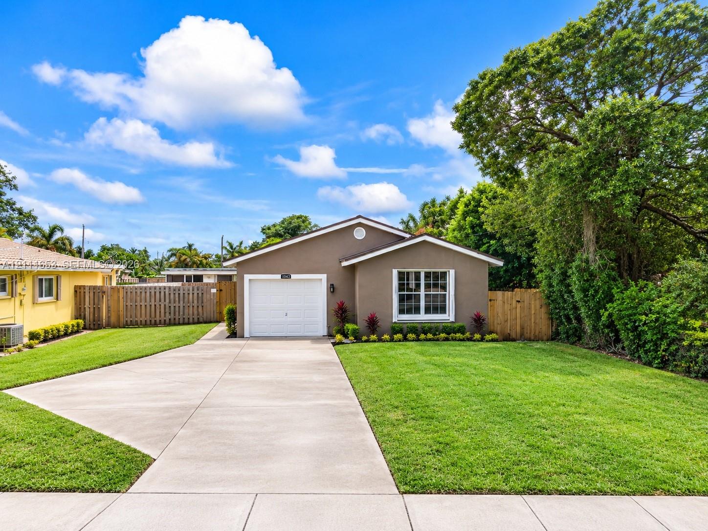 Single-story residence featuring a concrete driveway, attached garage, and wood privacy fencing