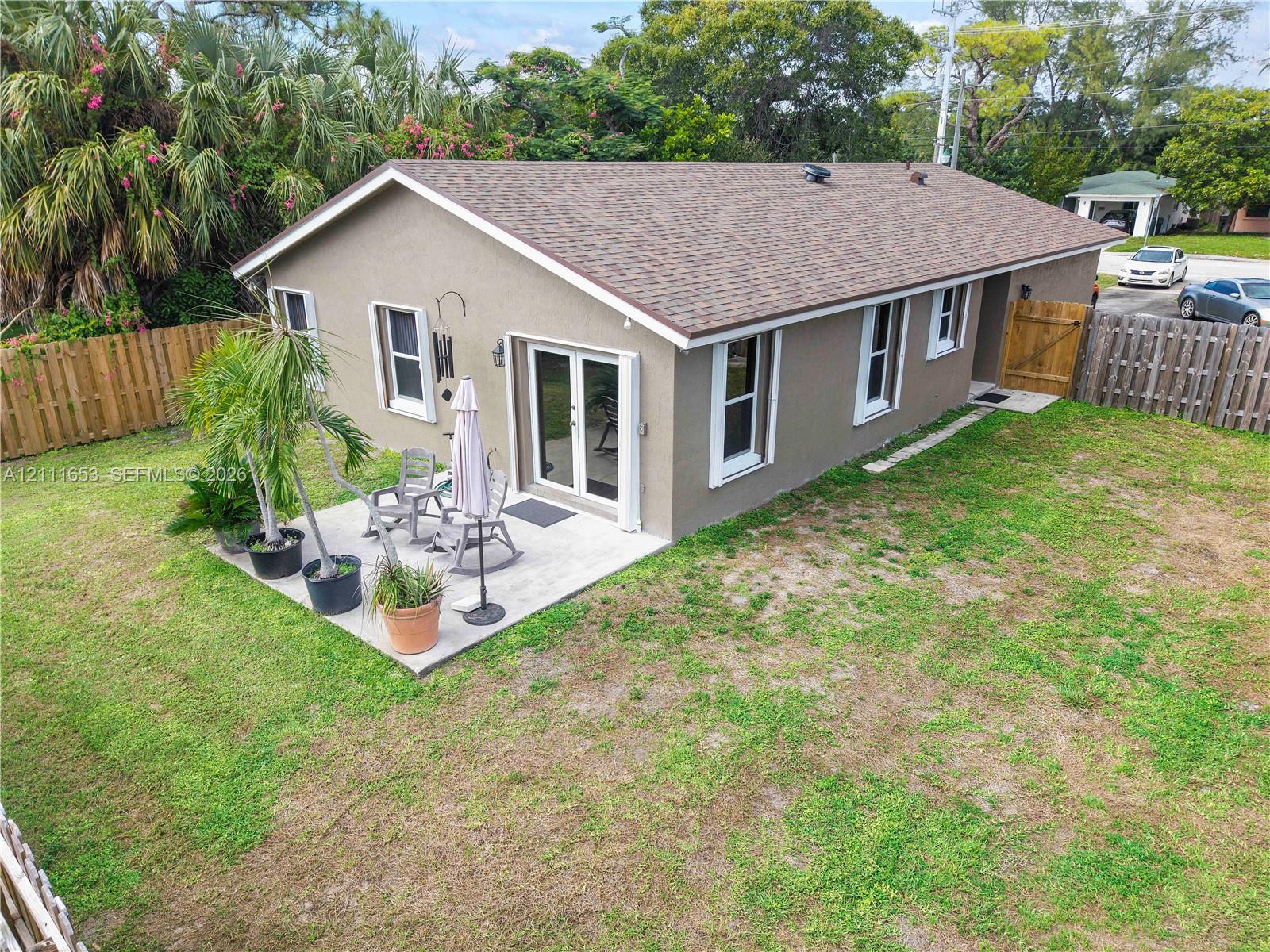 Paved backyard patio, double glass doors, and wood-panel perimeter fencing