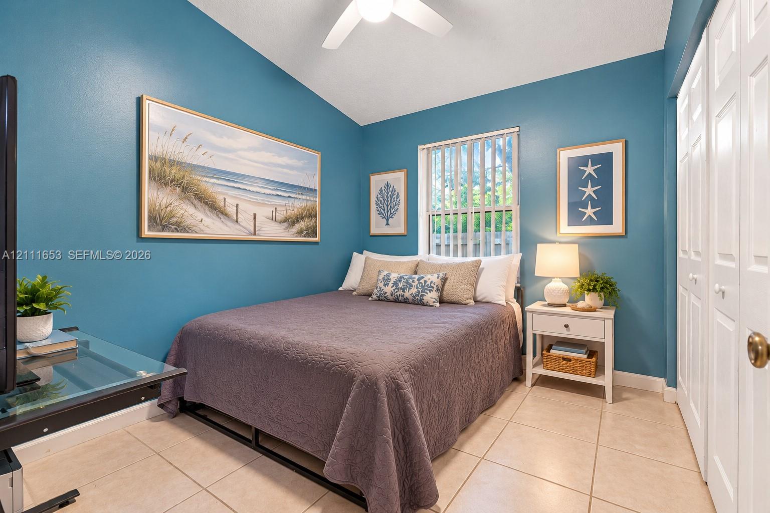 Bedroom 2 vaulted ceiling, ceramic tile flooring, vertical window blinds, and dual-panel closet doors Bedroom 2 vaulted ceiling, ceramic tile flooring, vertical window blinds, and dual-panel closet doors