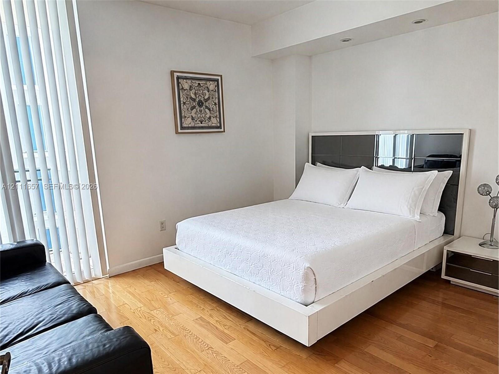 Wood-finish flooring, full-height vertical window blinds, and recessed ceiling lighting