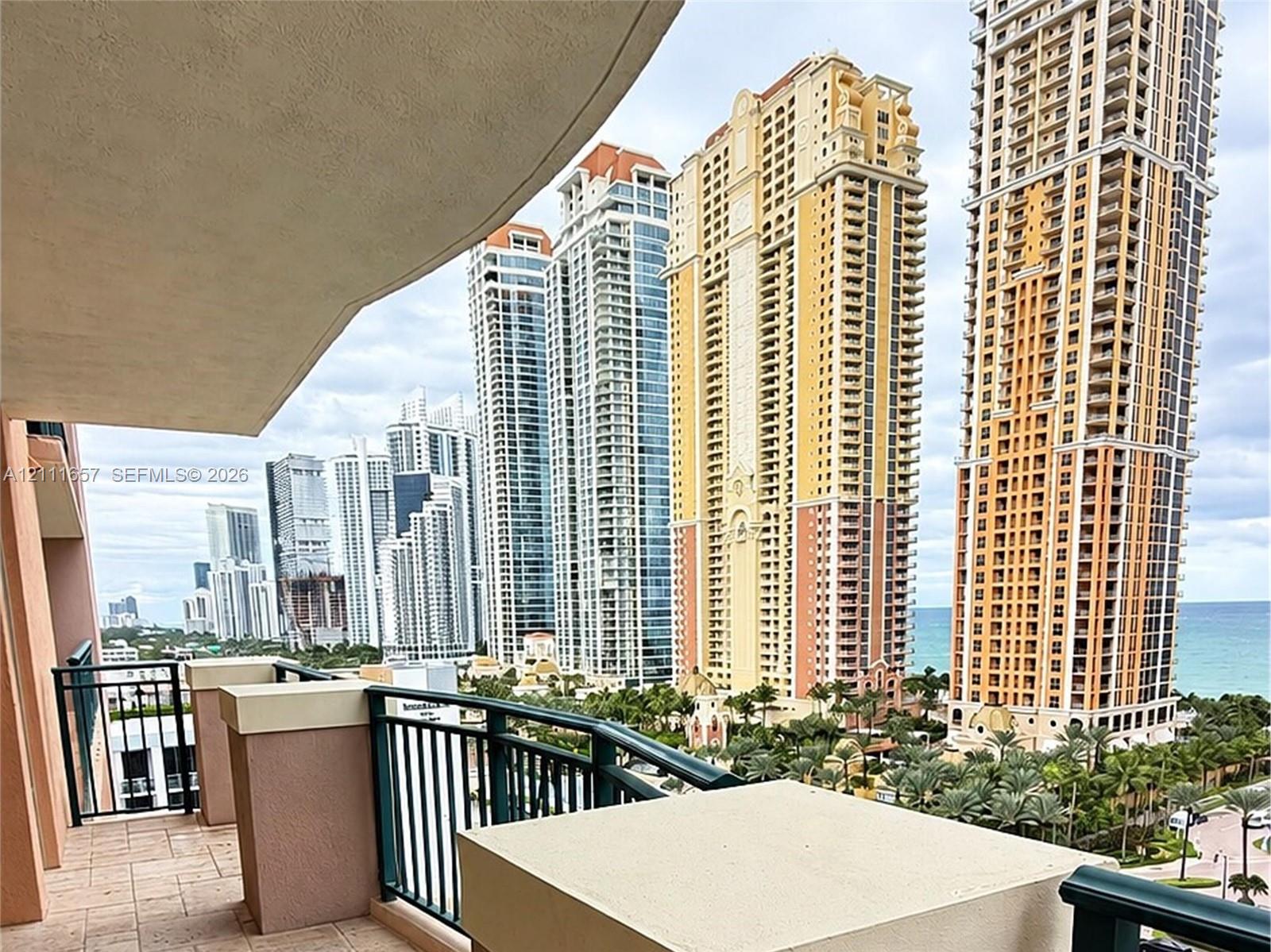 Private balcony featuring stone-tiled flooring, stucco-finished structural pillars with flat stone caps, and dark metal railings
