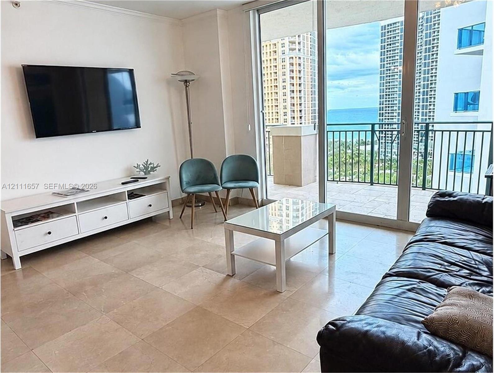 Large-format tile flooring, floor-to-ceiling glass sliding doors, and a private balcony with metal railing