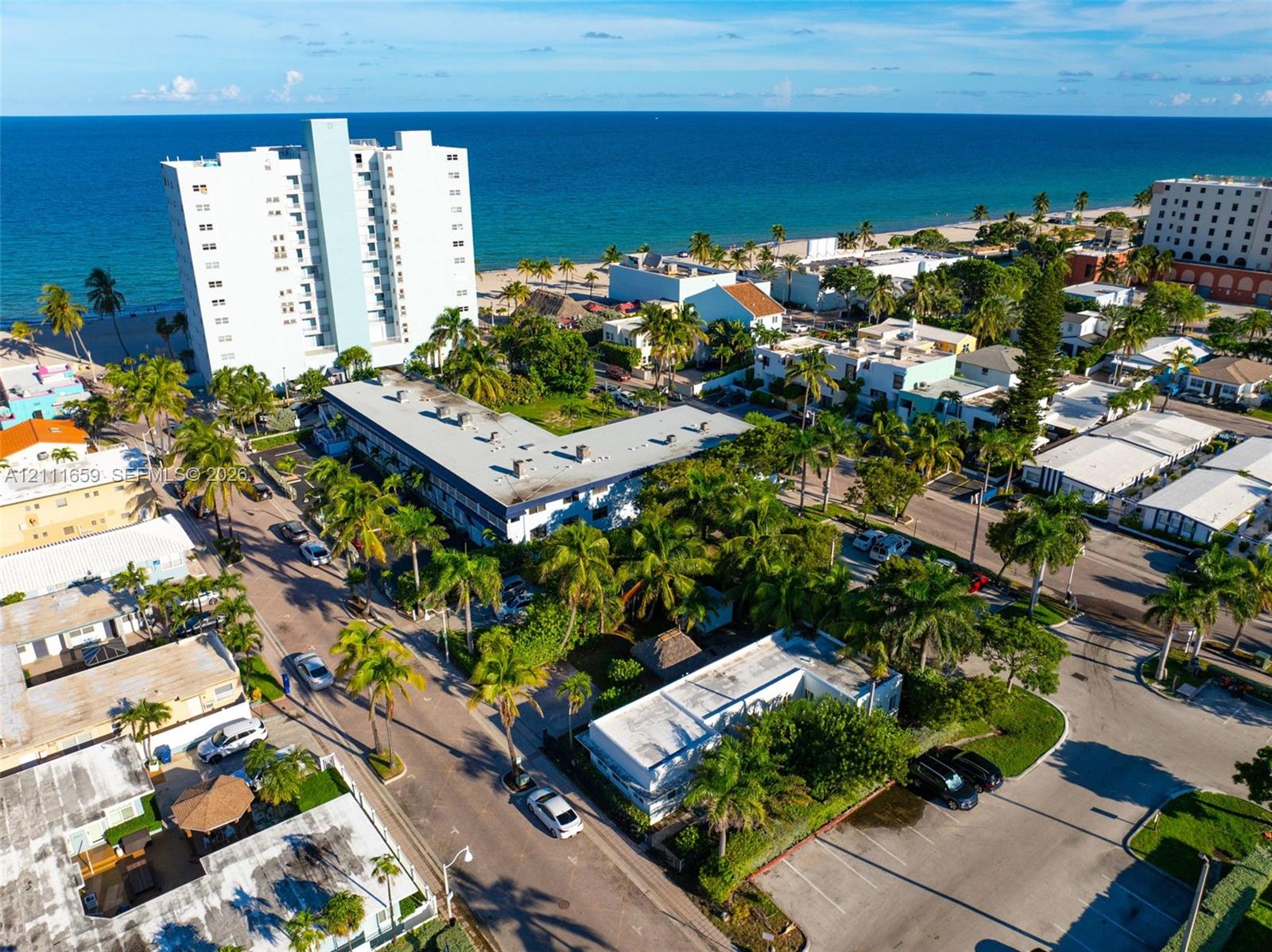 Coastal location featuring proximity to the shoreline, mature palm trees, paved surface parking, and multi-story architectural structures