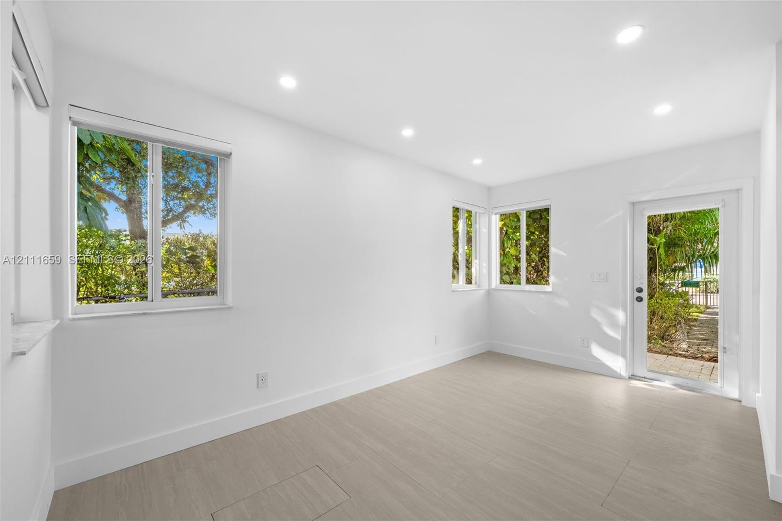 Interior space featuring wood-finish flooring, recessed lighting, white walls, large windows, and a glass-paneled exterior door