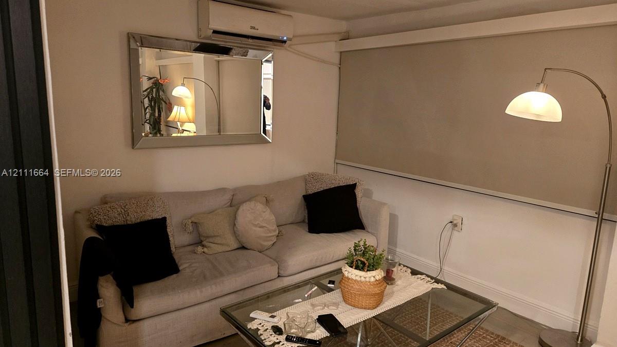 Wall-mounted ductless air conditioning unit, rectangular wall mirror with a beveled frame, and wide-format roller window shade