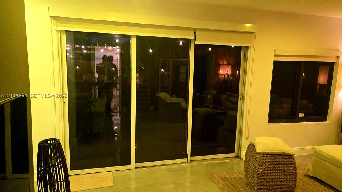 Large sliding glass doors with roller shades and a square-pane window featuring dark frames and smooth-finish interior walls
