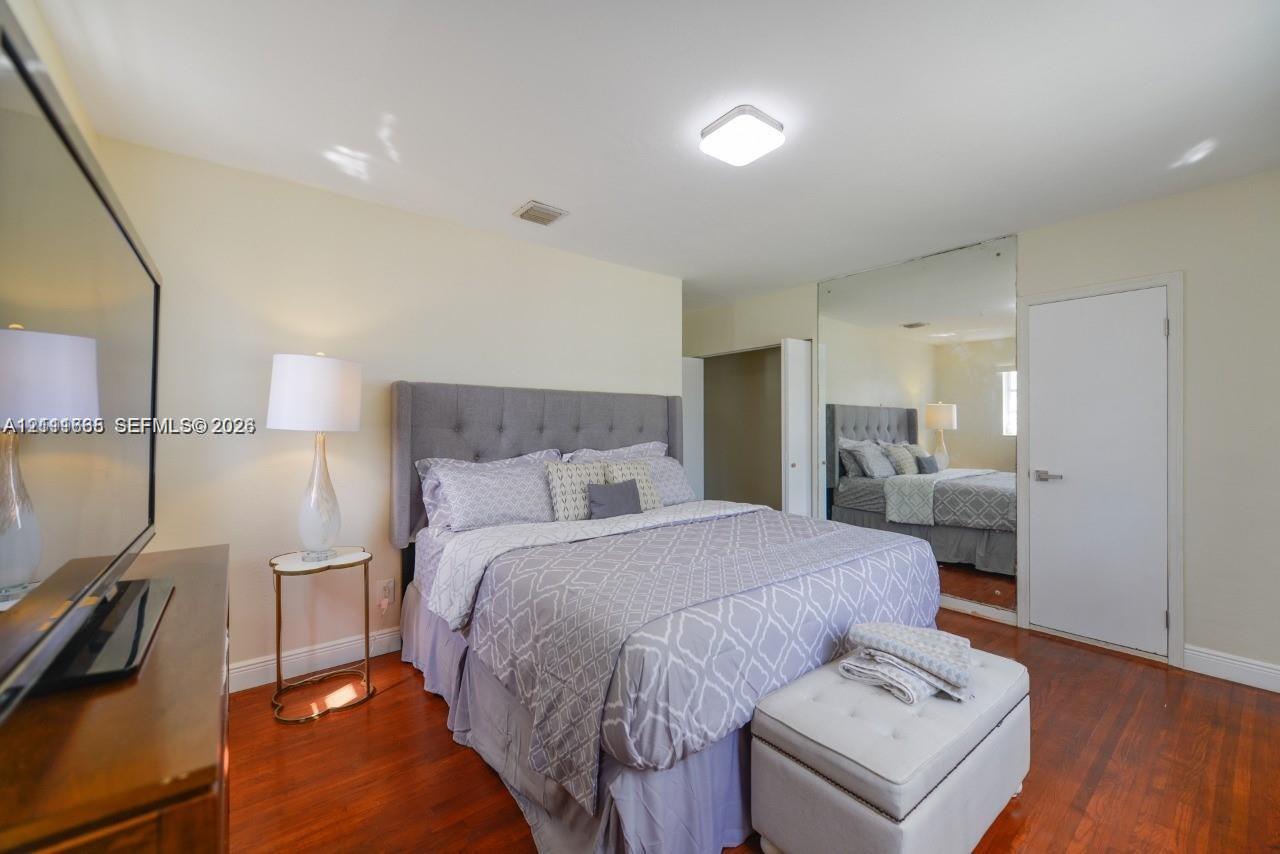 Bedroom featuring wood-finish flooring, full-wall mirrored closet doors, and a ceiling-mounted light fixture