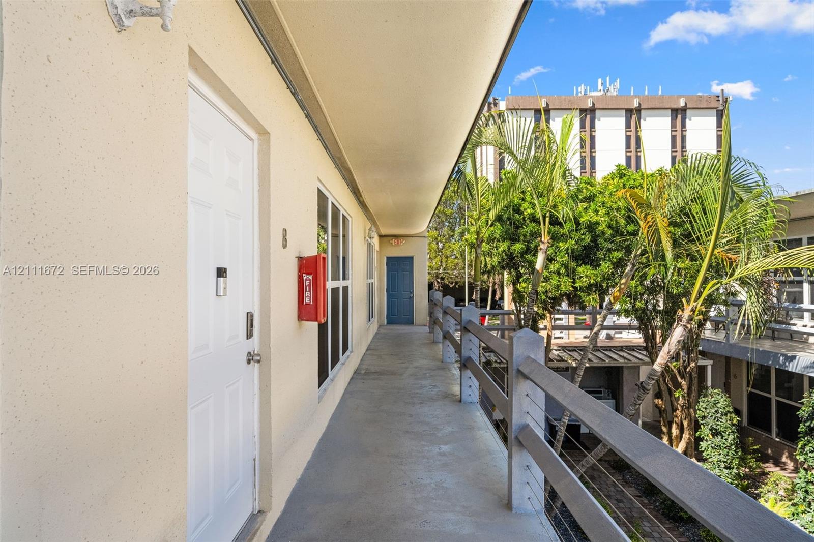 Exterior walkway featuring a concrete floor, horizontal metal railing, and a covered overhang