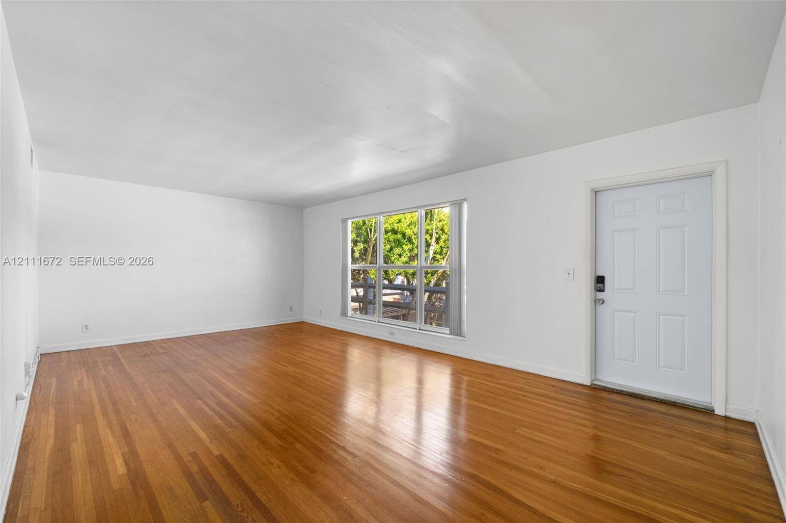 Interior space featuring wood-finish flooring, a multi-pane window with natural light, and a paneled entry door