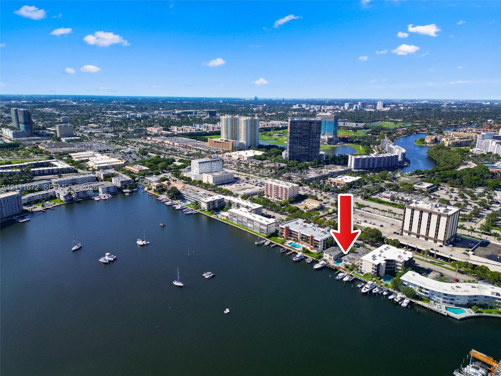 Aerial perspective of waterfront property featuring direct canal access, boat slips, and a ground-level swimming pool
