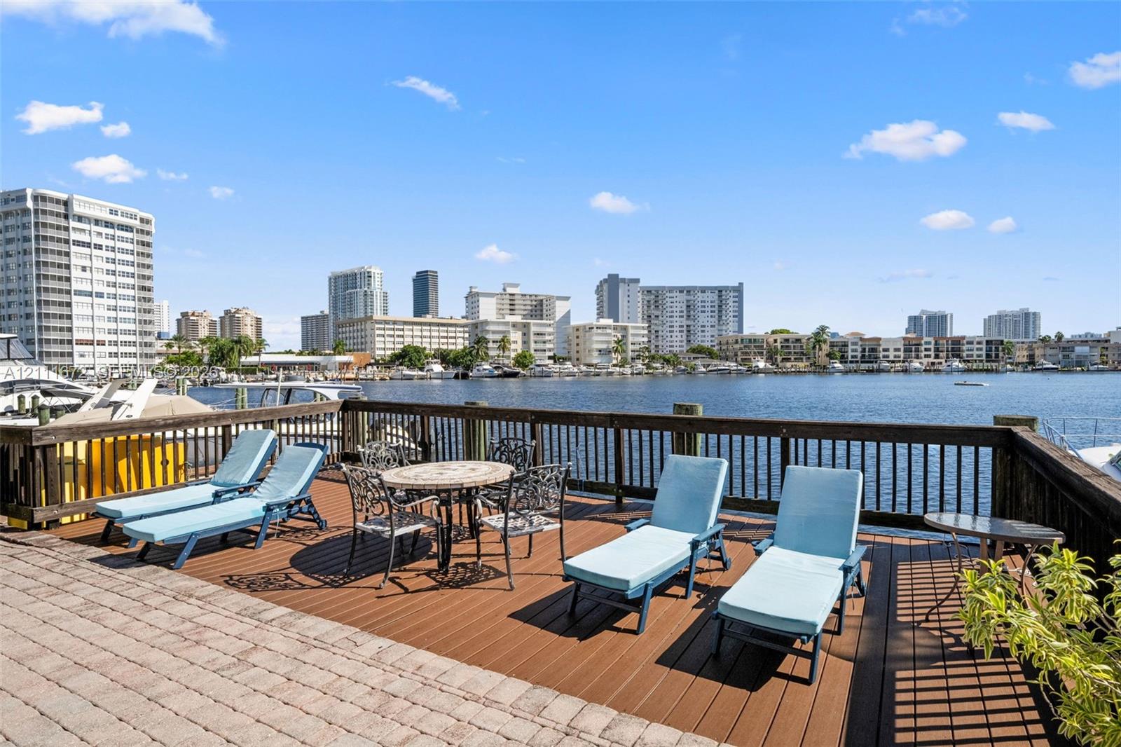 Waterfront terrace featuring composite decking, paved hardscaping, and a wooden perimeter railing Waterfront terrace featuring composite decking, paved hardscaping, and a wooden perimeter railing