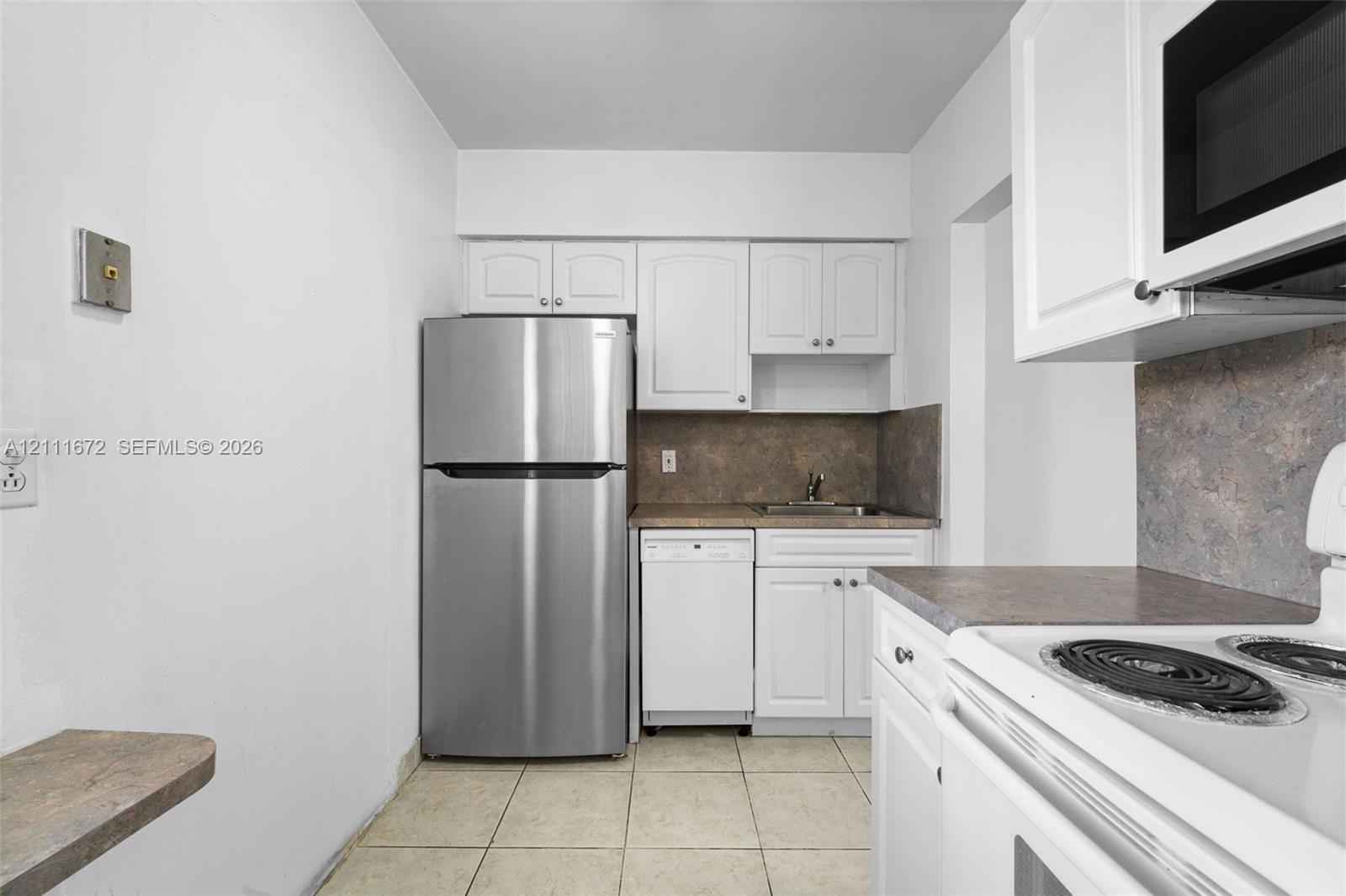 Kitchen featuring white shaker-style cabinetry, stainless steel refrigerator, white electric range, integrated dishwasher, and stone-finish backsplash