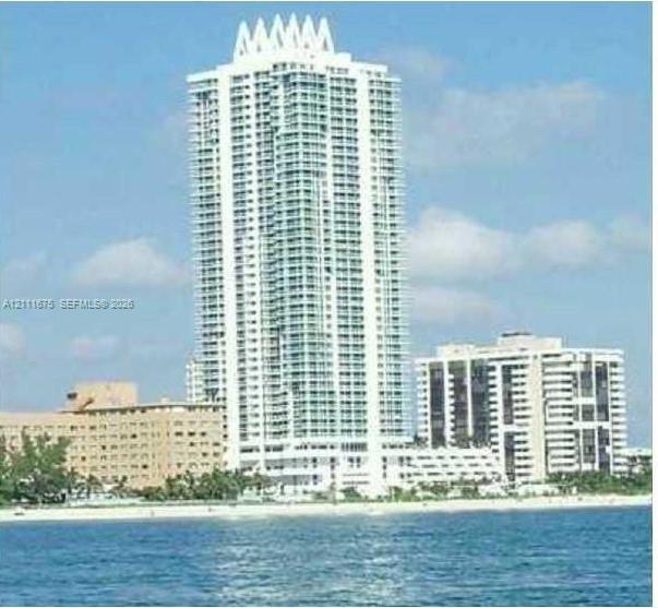 High-rise tower featuring a crown architectural detail, glass-enclosed balconies, and direct coastal proximity