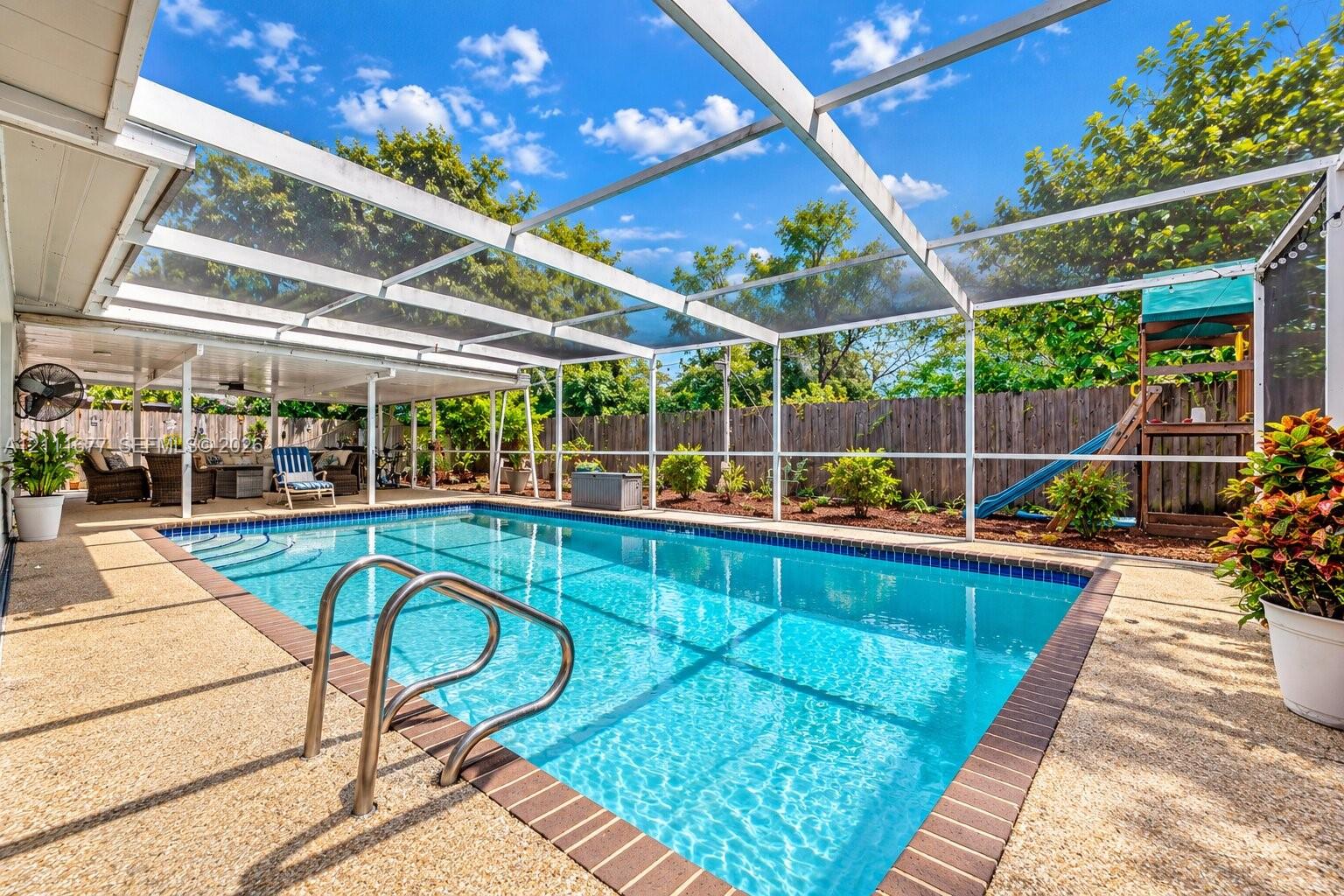 Screened-in pool area featuring a pebble-finish pool deck, brick coping, stainless steel ladder, and a covered lanai Screened-in pool area featuring a pebble-finish pool deck, brick coping, stainless steel ladder, and a covered lanai