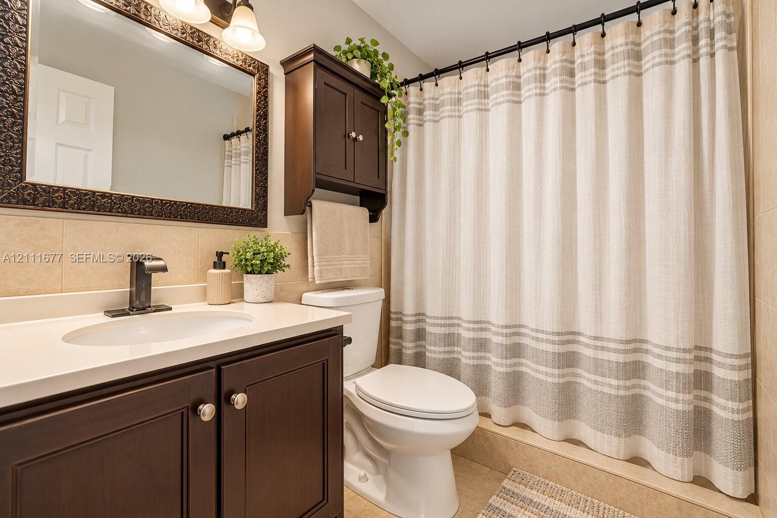 Bathroom vanity featuring dark-toned cabinetry, a solid-surface countertop with an integrated basin, a wall-mounted medicine cabinet, and a single-handle matte black faucet