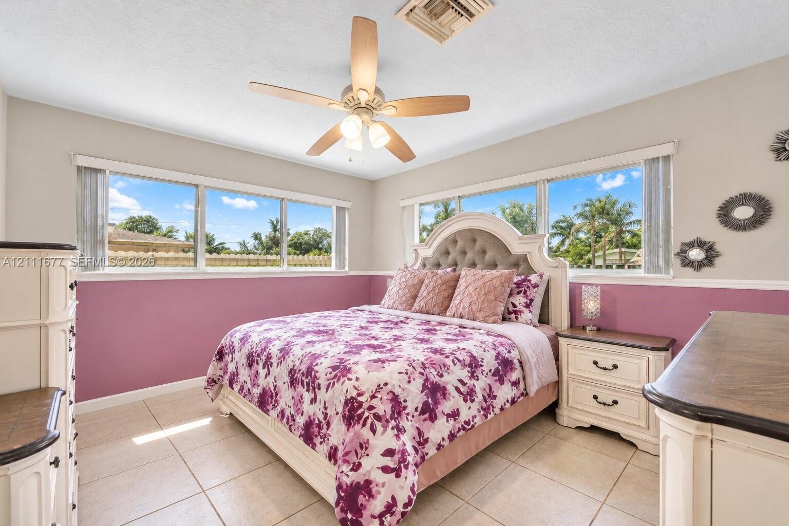 Neutral wall finish with wainscoting, ceramic tile flooring, and multi-light ceiling fan