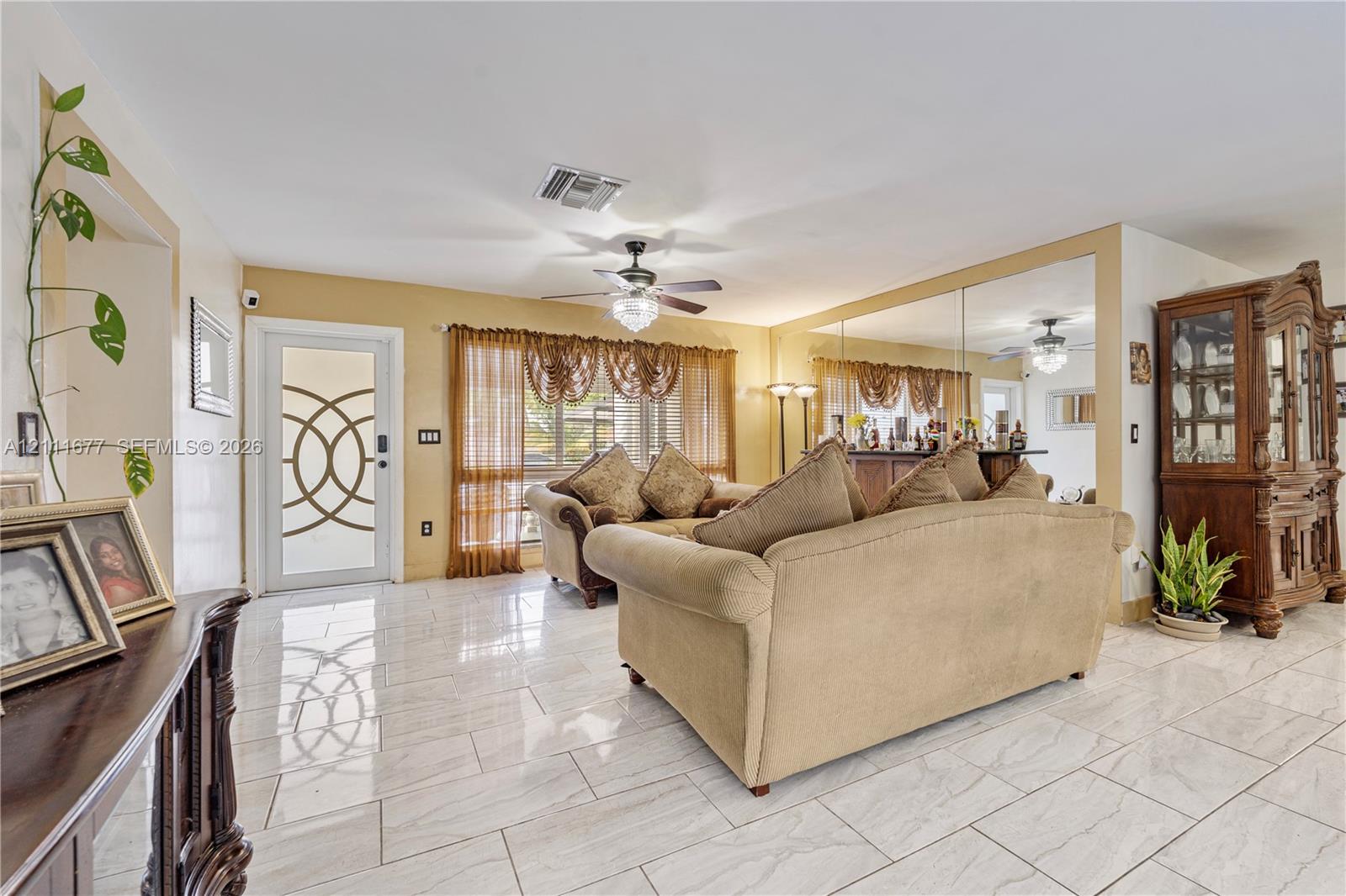 Ceramic tile flooring, mirrored wall paneling, and an exterior door with geometric glass inserts
