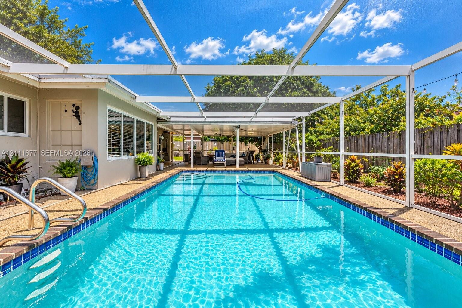 Screened lanai featuring a swimming pool, tiled pool coping, metallic handrails, and a covered patio area Screened lanai featuring a swimming pool, tiled pool coping, metallic handrails, and a covered patio area
